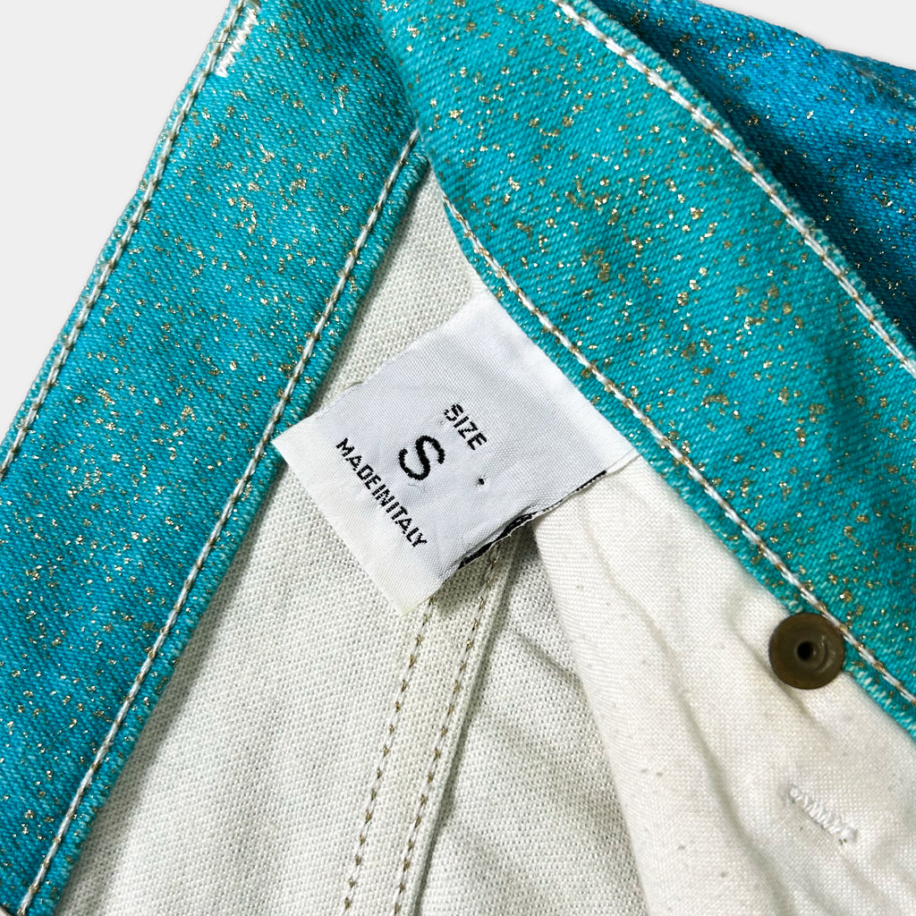 A close-up view of a pair of blue jeans with a white label attached, indicating the size.