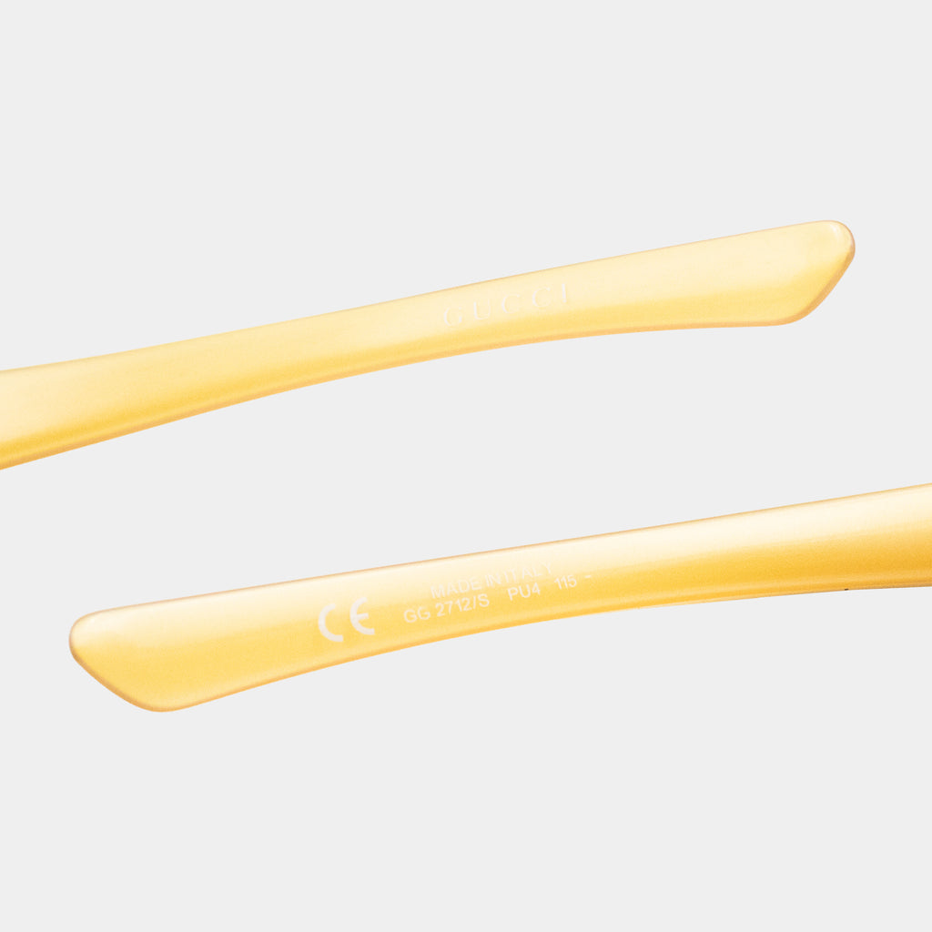 a pair of yellow-colored sunglasses with a focus on the frame and the text "Gucci" on the frame.