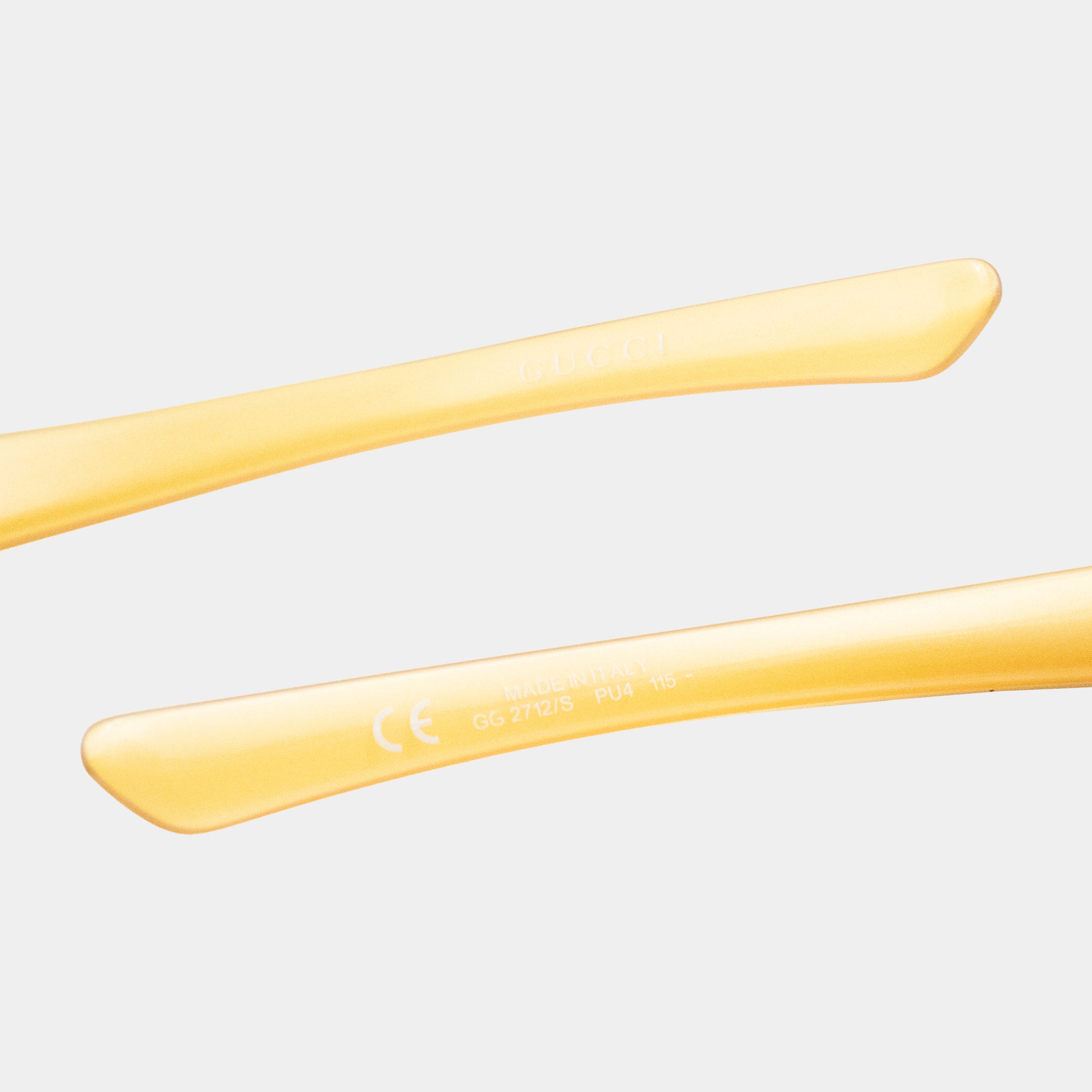 a pair of yellow-colored sunglasses with a focus on the frame and the text "Gucci" on the frame.
