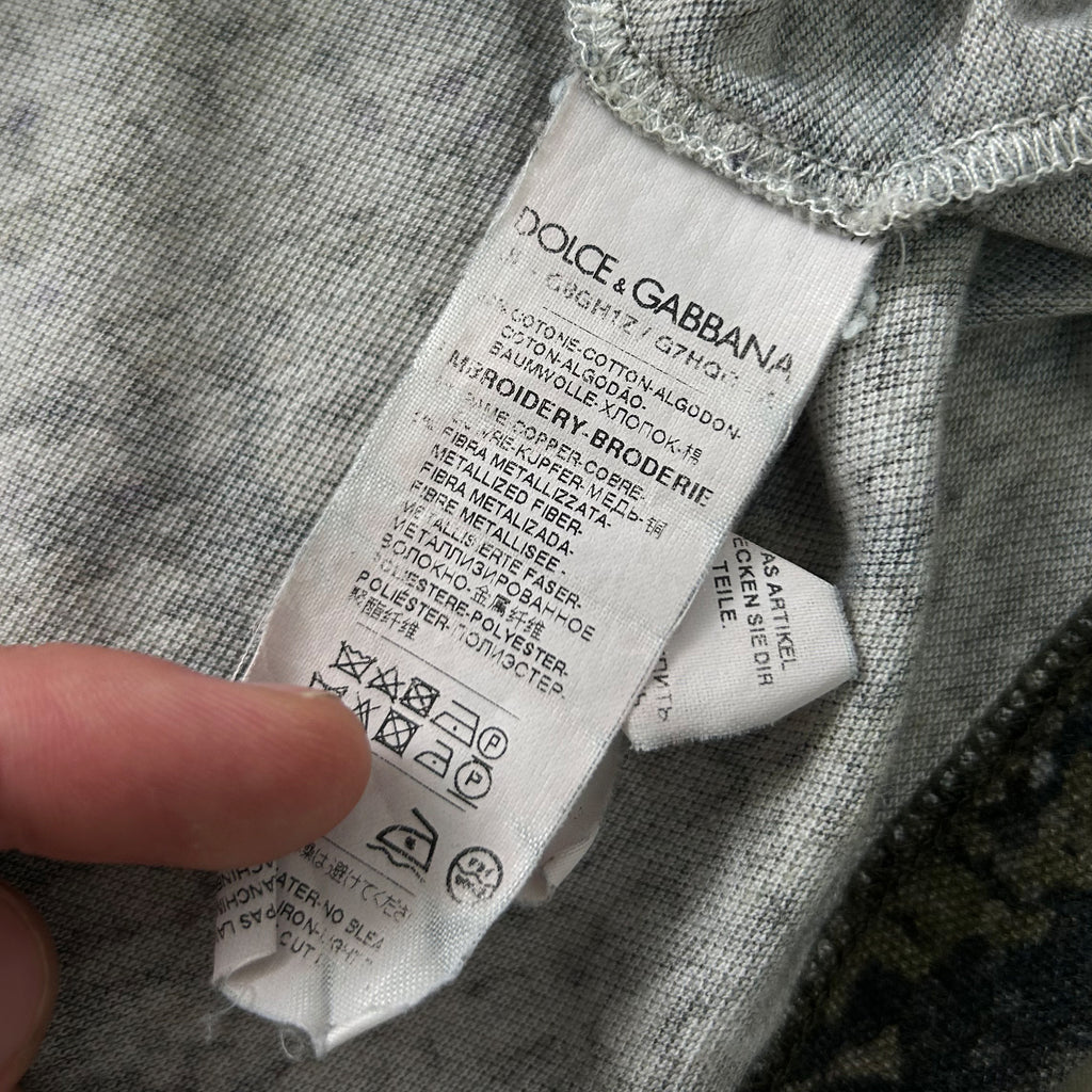 A close-up view of a clothing label, with a person's finger pointing to it.