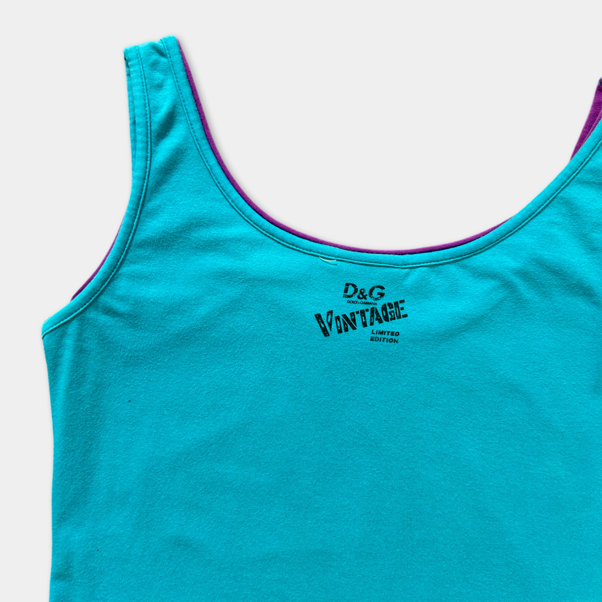 A turquoise tank top with a purple collar and the text "D.G. VINTAGE EDITION" printed on it.