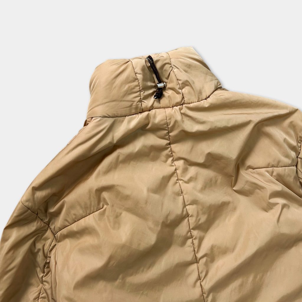 A beige jacket with a zipper pull and a black pull tab visible on the collar.