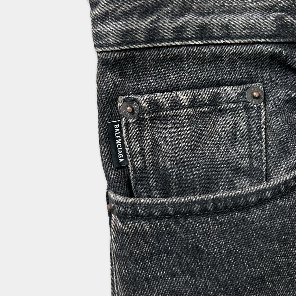 A close-up view of a pair of black denim jeans, showing the pocket and the brand name "BALENCIA" printed on a label.