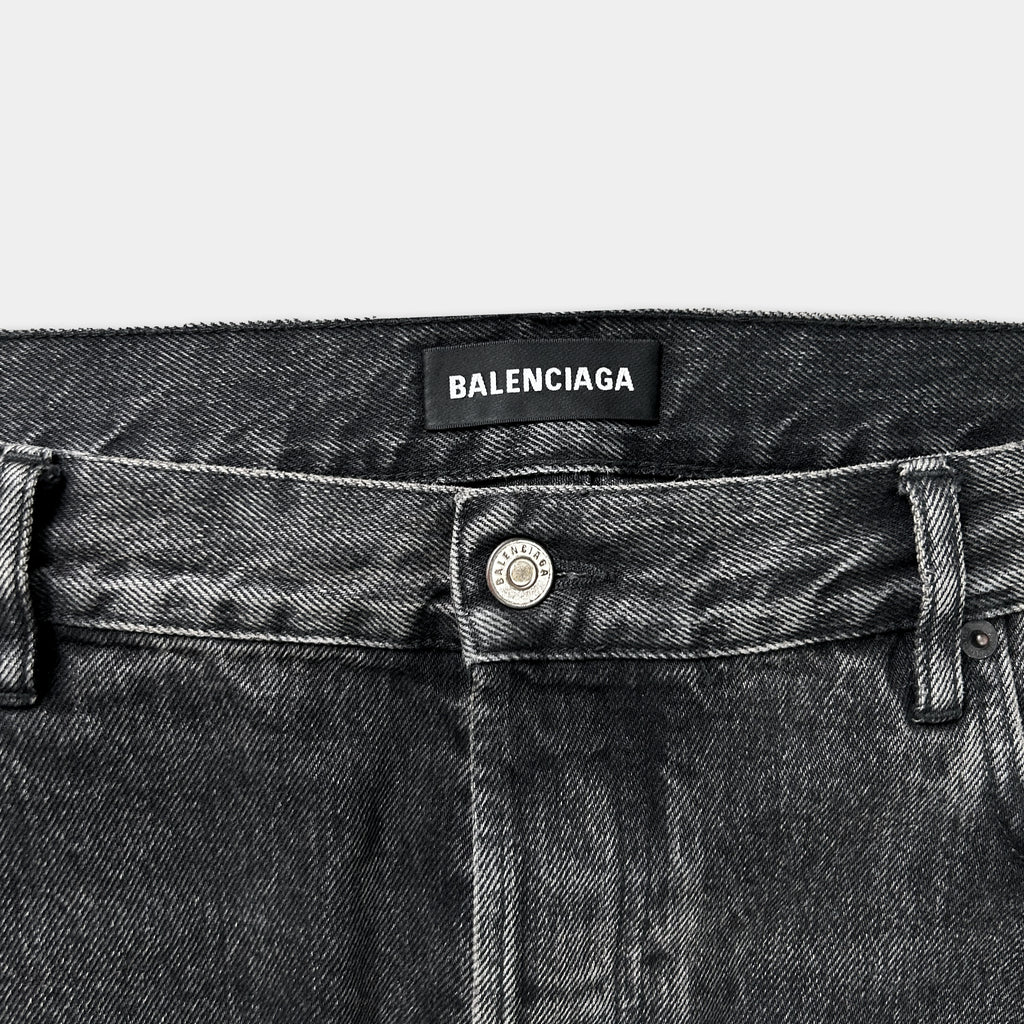 A close-up view of a pair of black Balenciaga jeans, with the brand's name visible on the waistband.