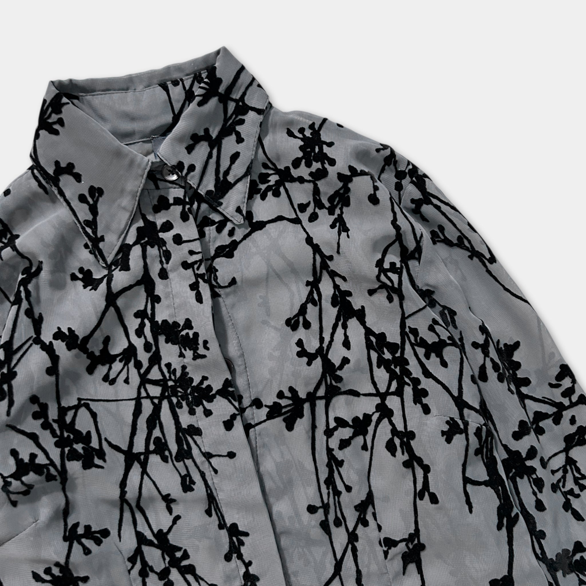 a gray blouse with a black floral pattern, featuring a collar and sleeves.
