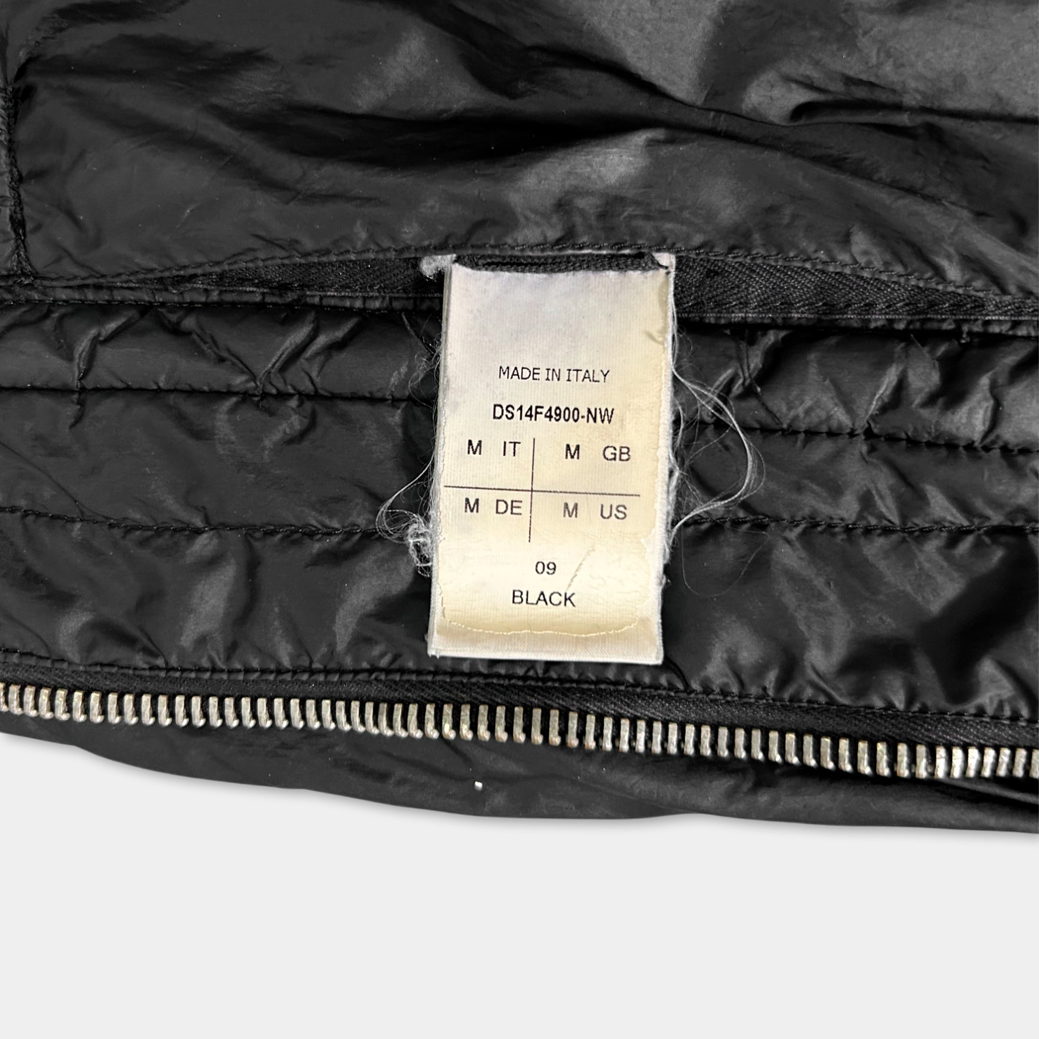 a close-up view of a black jacket with a label attached to it, indicating the material and size information.