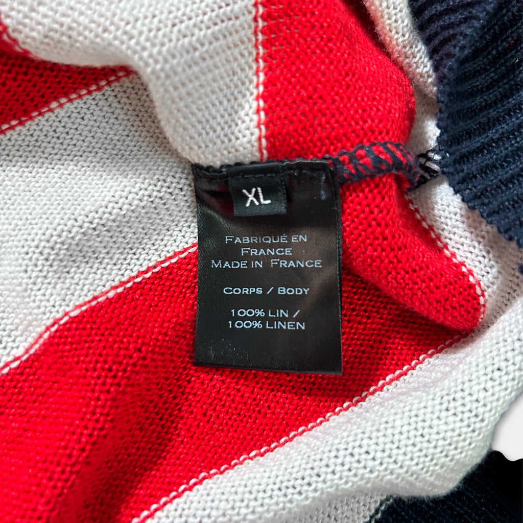 a close-up view of a red and white striped fabric, with a black label attached to it. The label provides information about the fabric, including that it is made in France, is 100% linen, and is a size XL.
