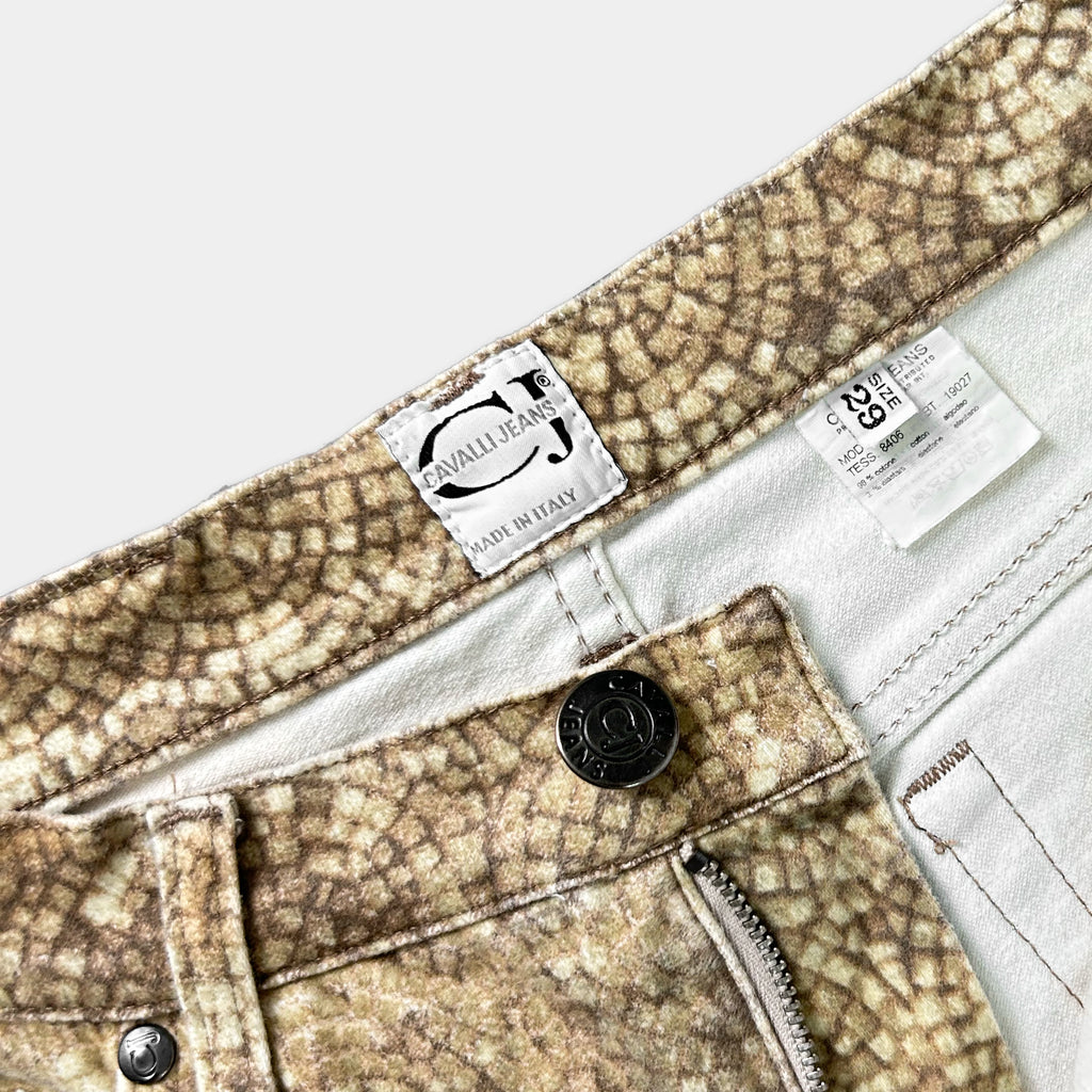 a close-up view of a pair of printed jeans, featuring a label and zipper detail.