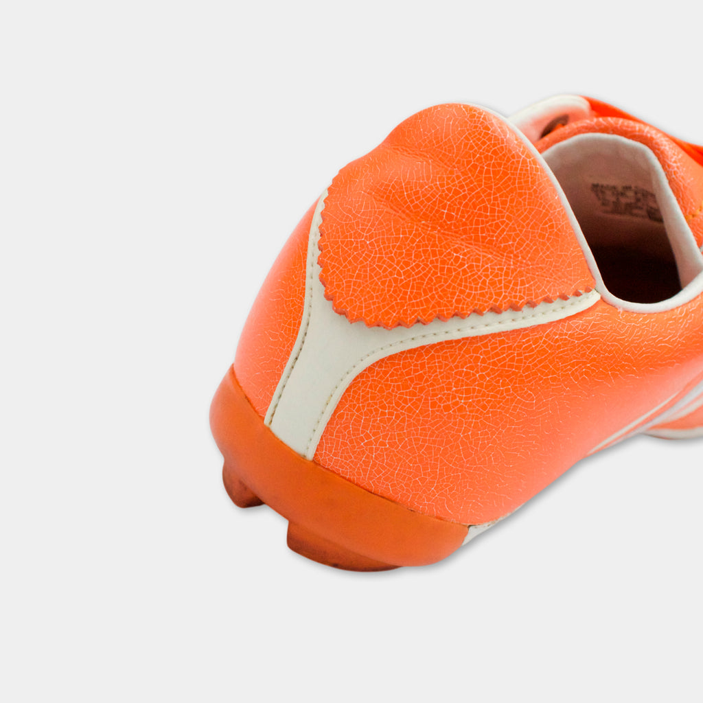 A close-up view of an orange and white shoe, with a scalloped edge and a white sole visible.
