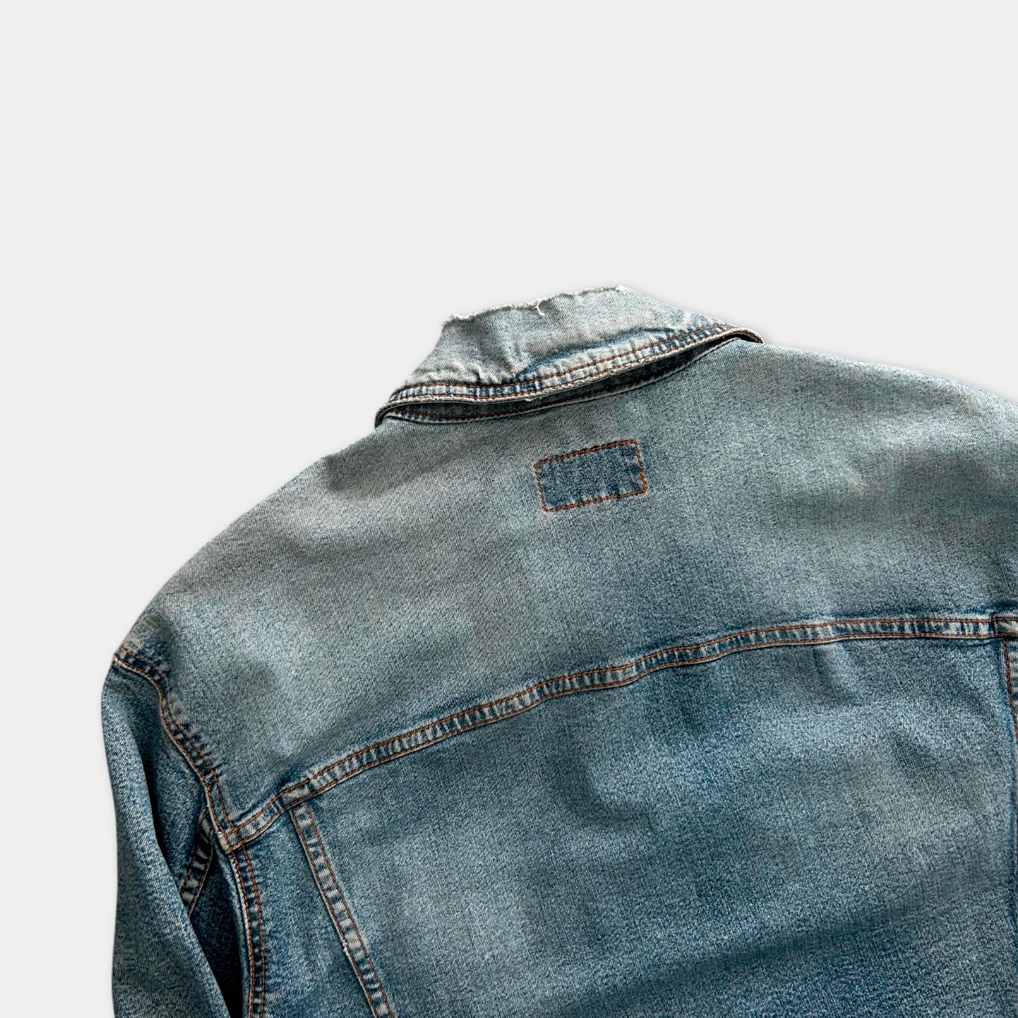 the back of a denim jacket with a small patch on the collar.