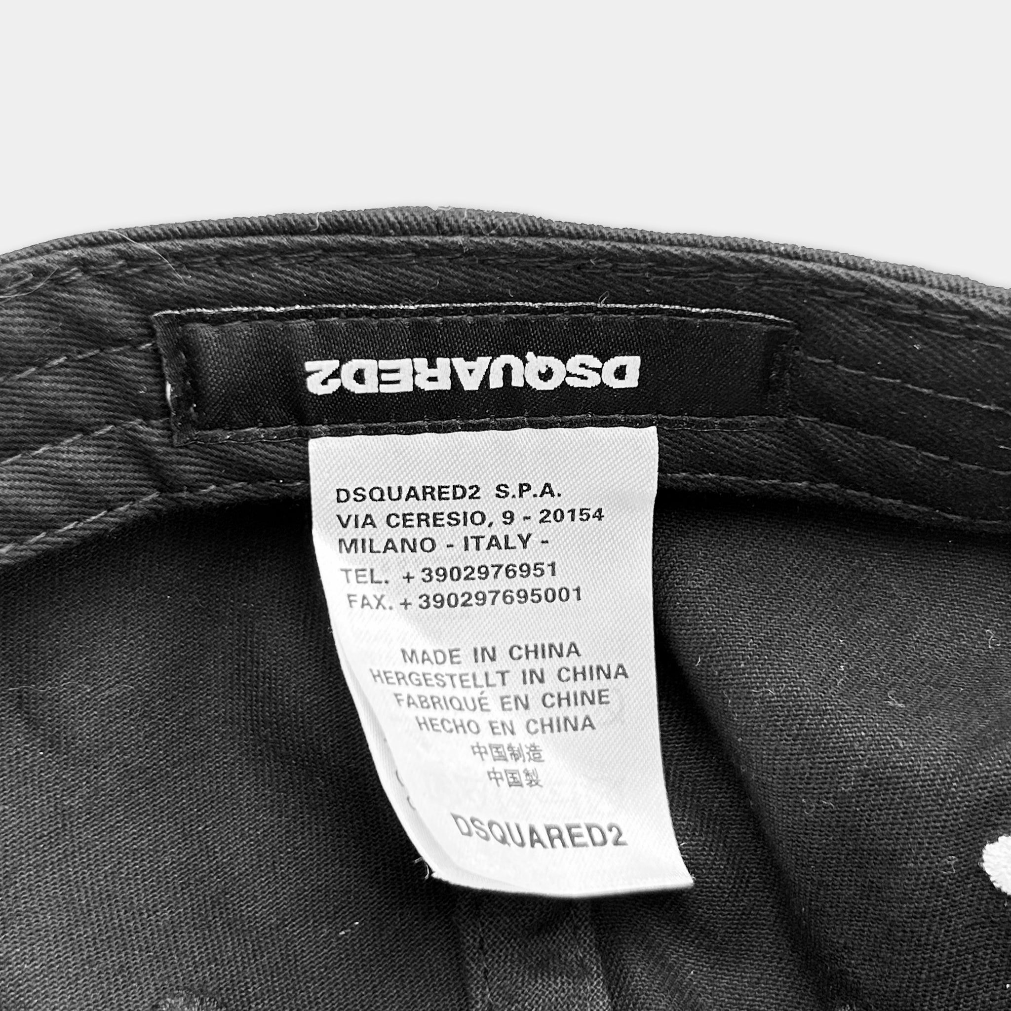 a close-up view of a black label on a black fabric, likely a piece of clothing or accessory, with white text.