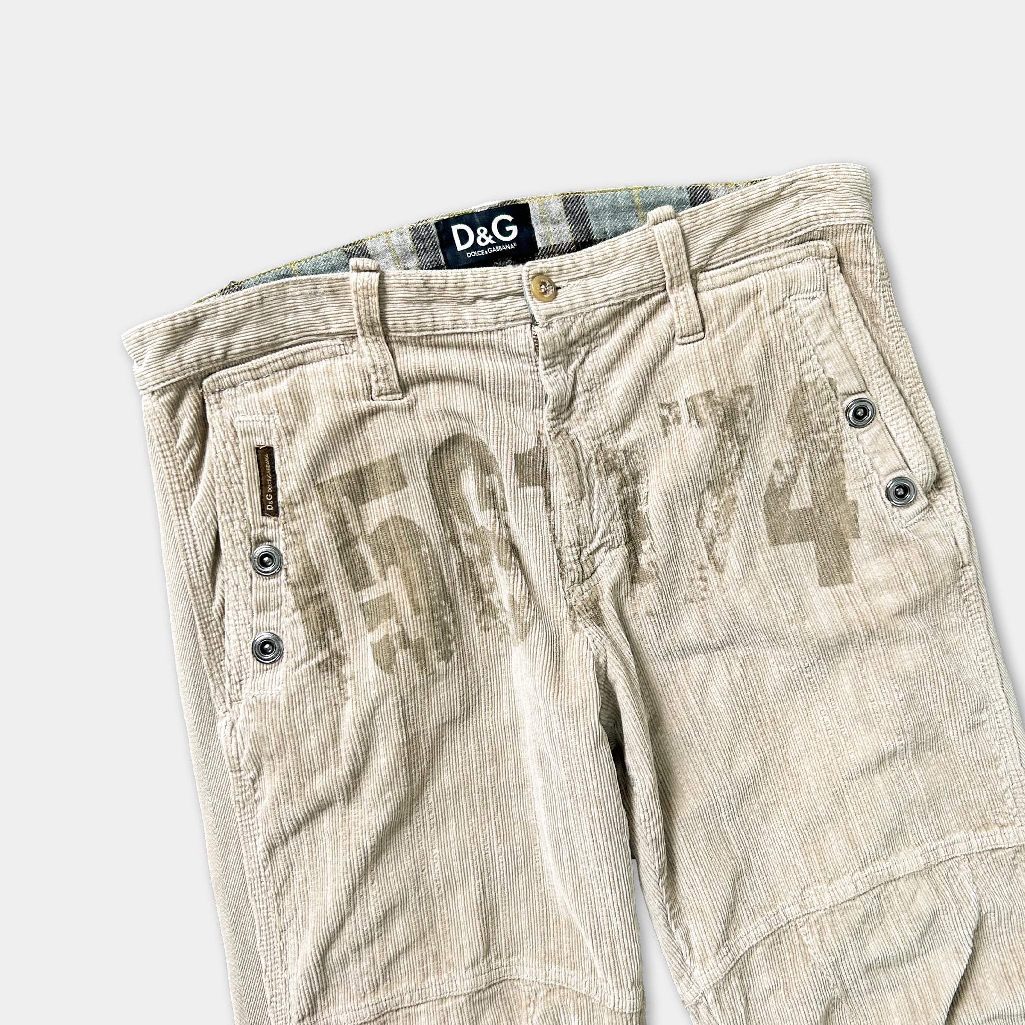 A pair of beige corduroy pants with a D&G logo on the waistband.