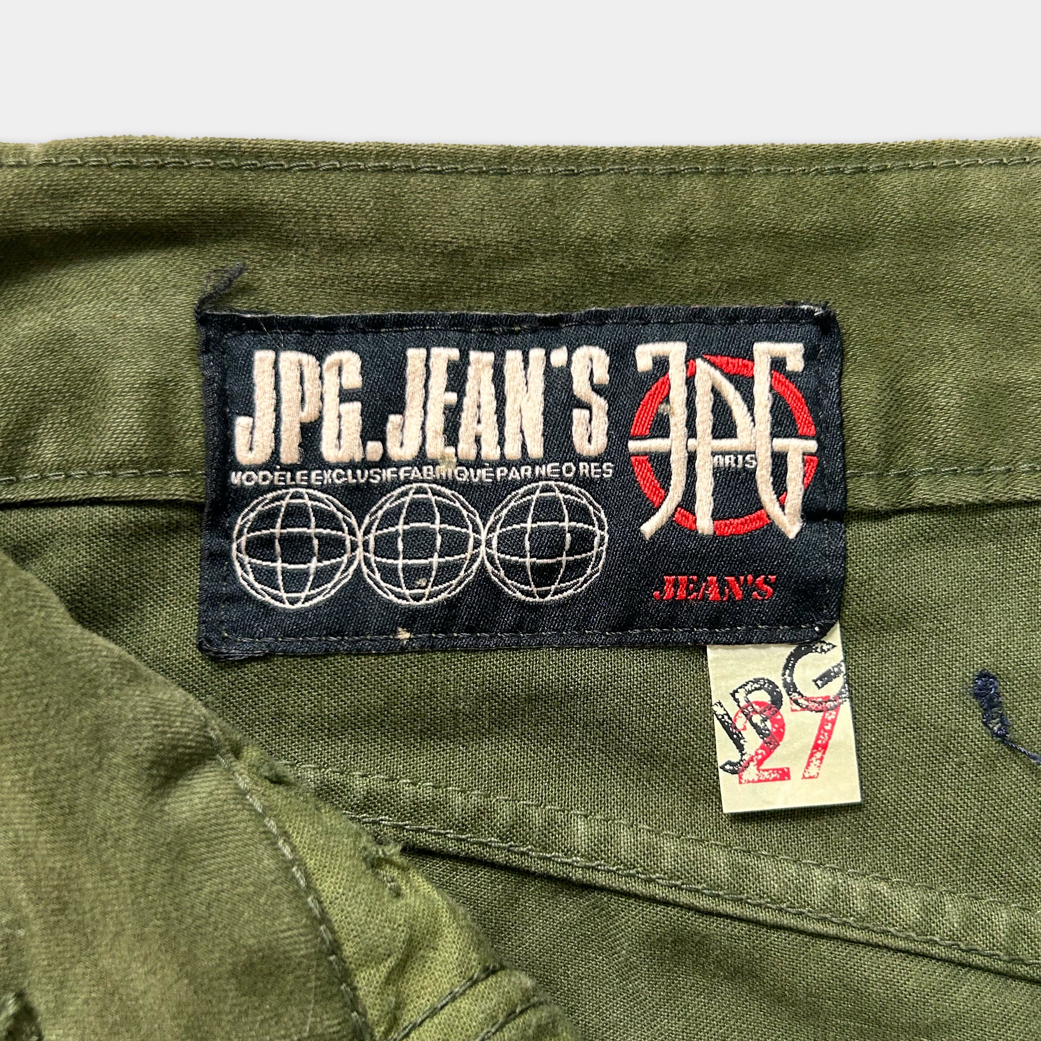 a close-up view of a green fabric, possibly a piece of clothing, with a label attached to it. The label appears to be a brand label for a product, possibly jeans.