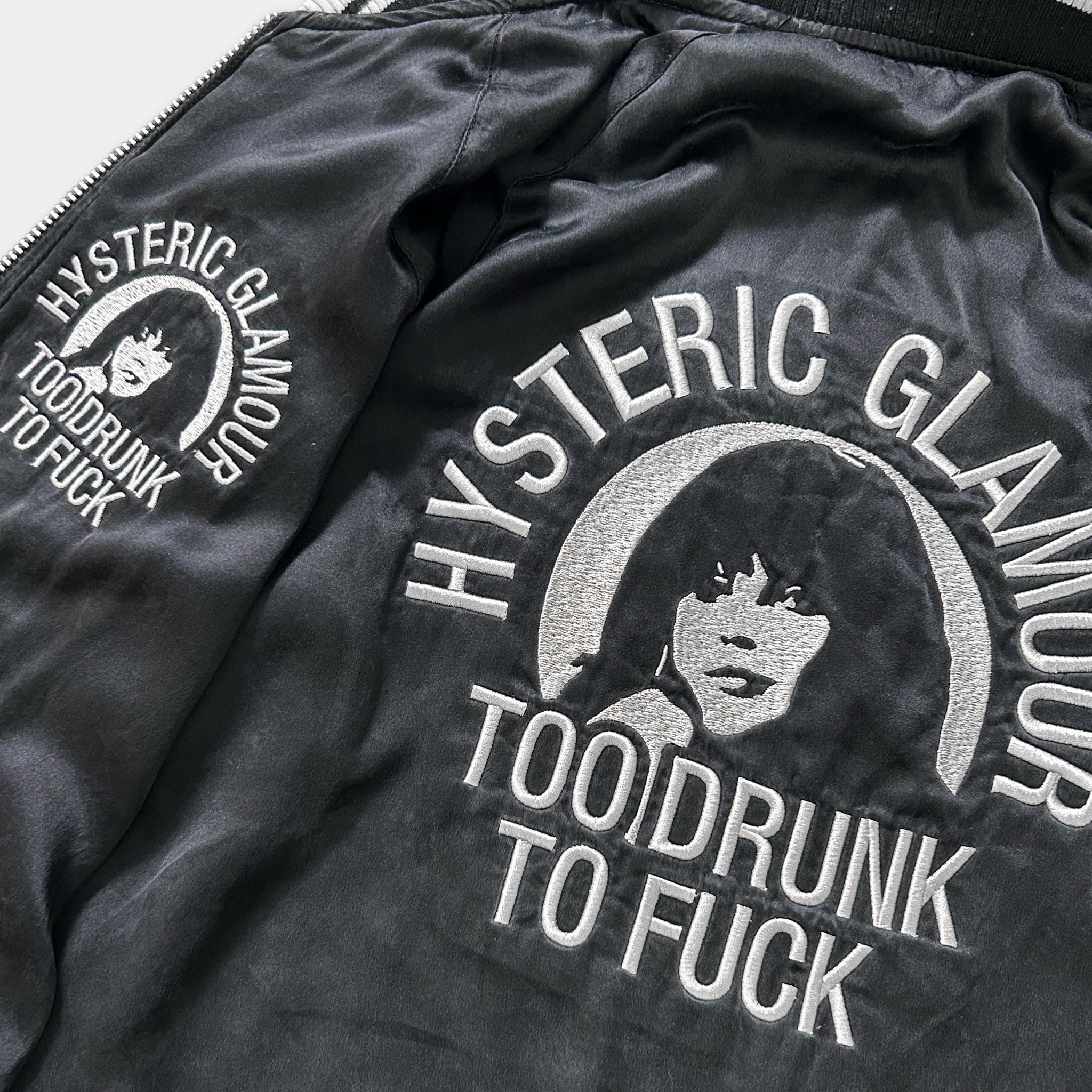 a close-up view of a black jacket with white text and an embroidered design on the back.