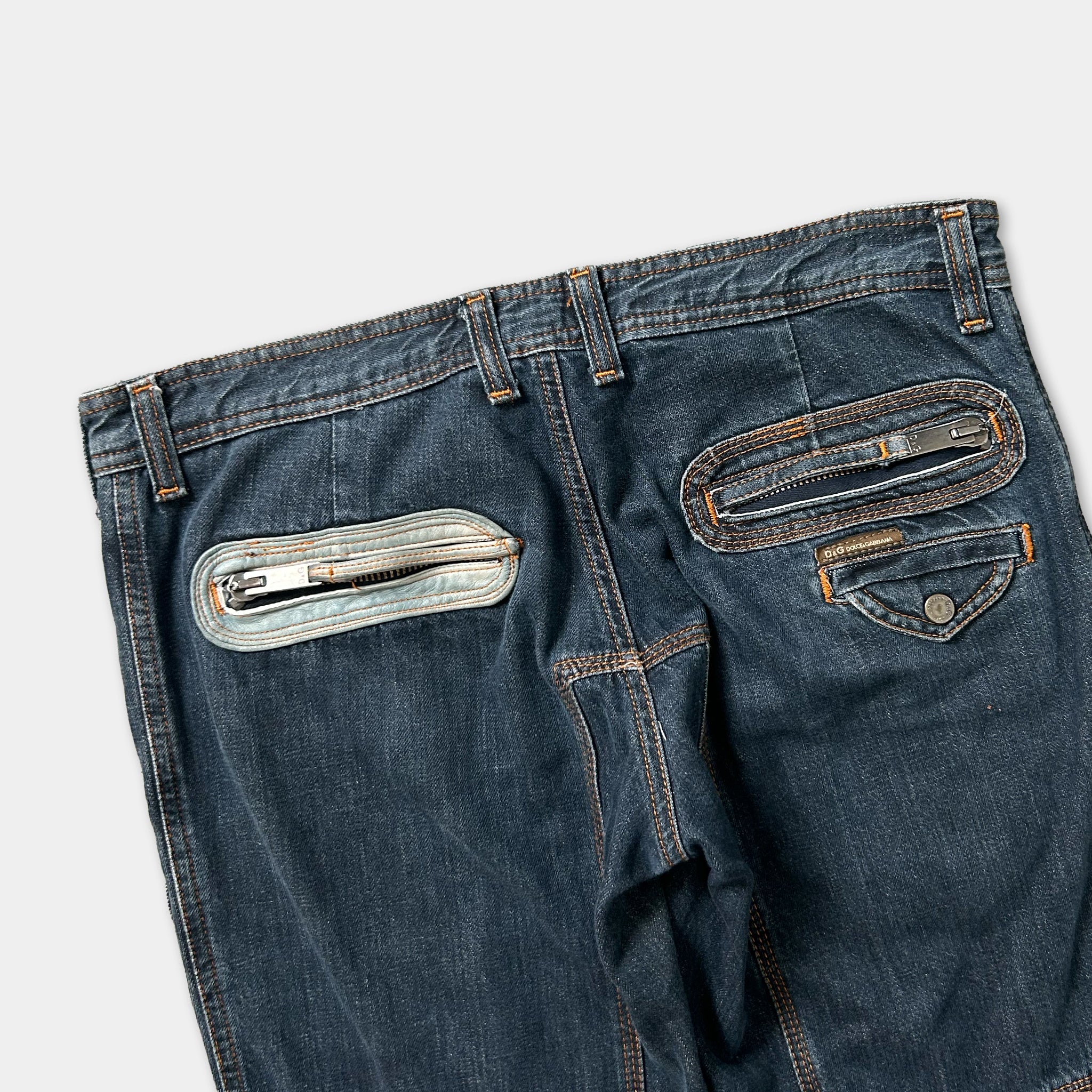 A pair of blue jeans with multiple zipper pockets and a zipper pull.