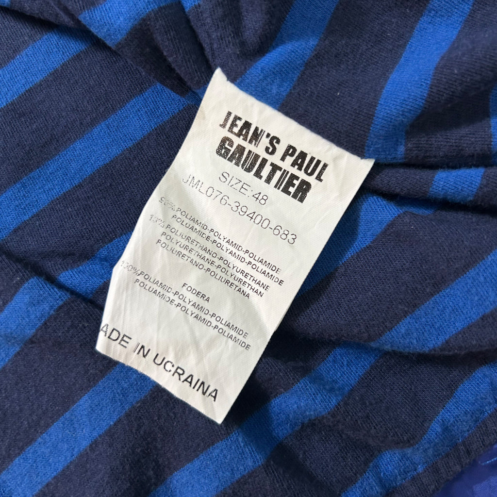 a close-up view of a label on a blue and black striped fabric, likely a garment or textile product.