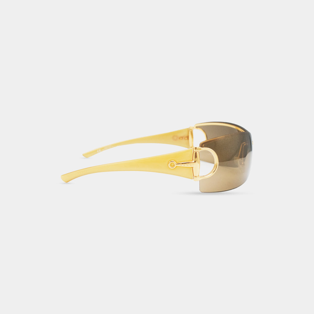 A pair of gold-colored sunglasses with a dark lens.