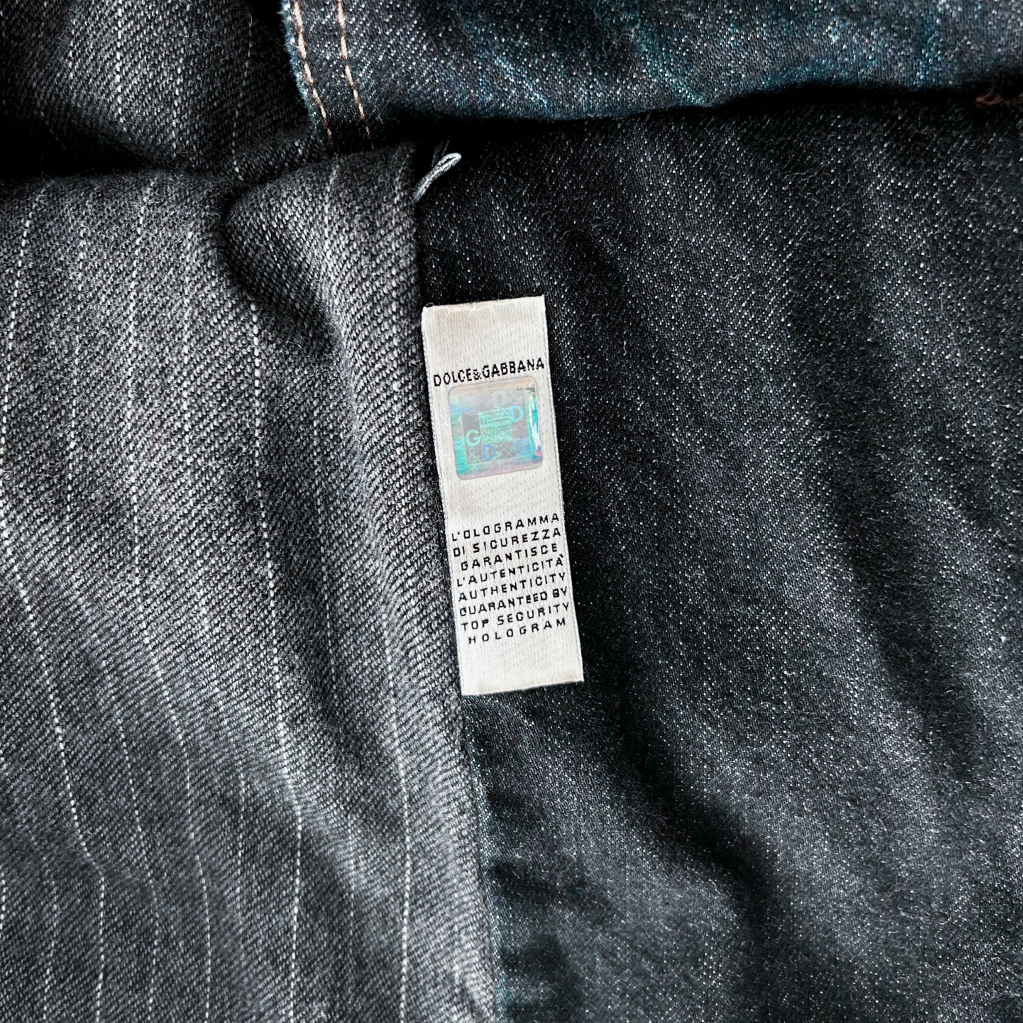 a close-up view of a denim fabric, possibly a pair of jeans, with a label attached to it. The label appears to contain text and possibly a barcode or QR code.