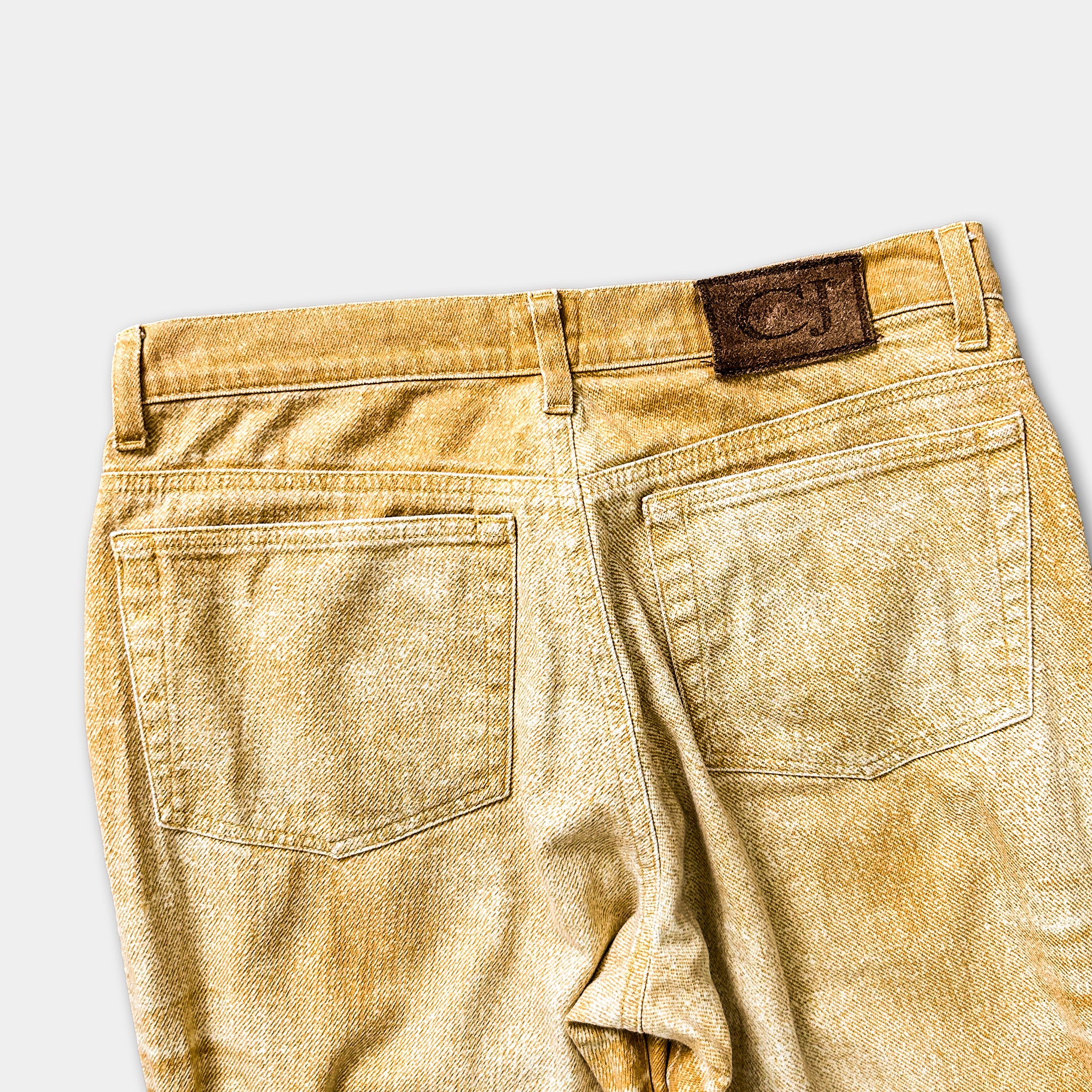 a pair of tan-colored jeans with a brown leather patch on the back pocket.