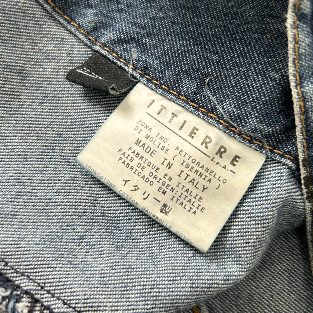 a close-up view of a denim fabric, specifically a pair of jeans, with a label attached to it. The label appears to be a label from a clothing brand, indicating that the jeans are made in Italy and are part of the brand's collection.