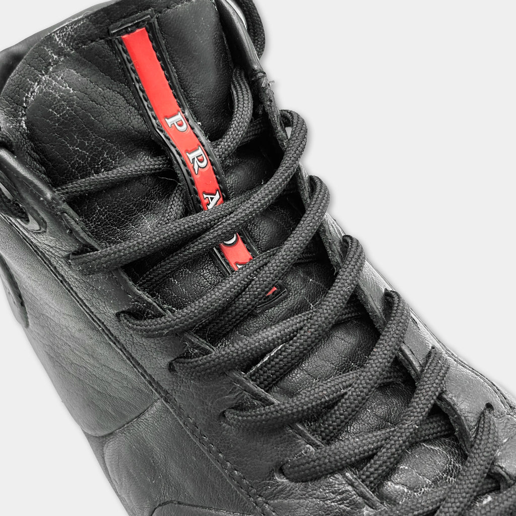 A close-up view of a black leather shoe with a red stripe on the side.