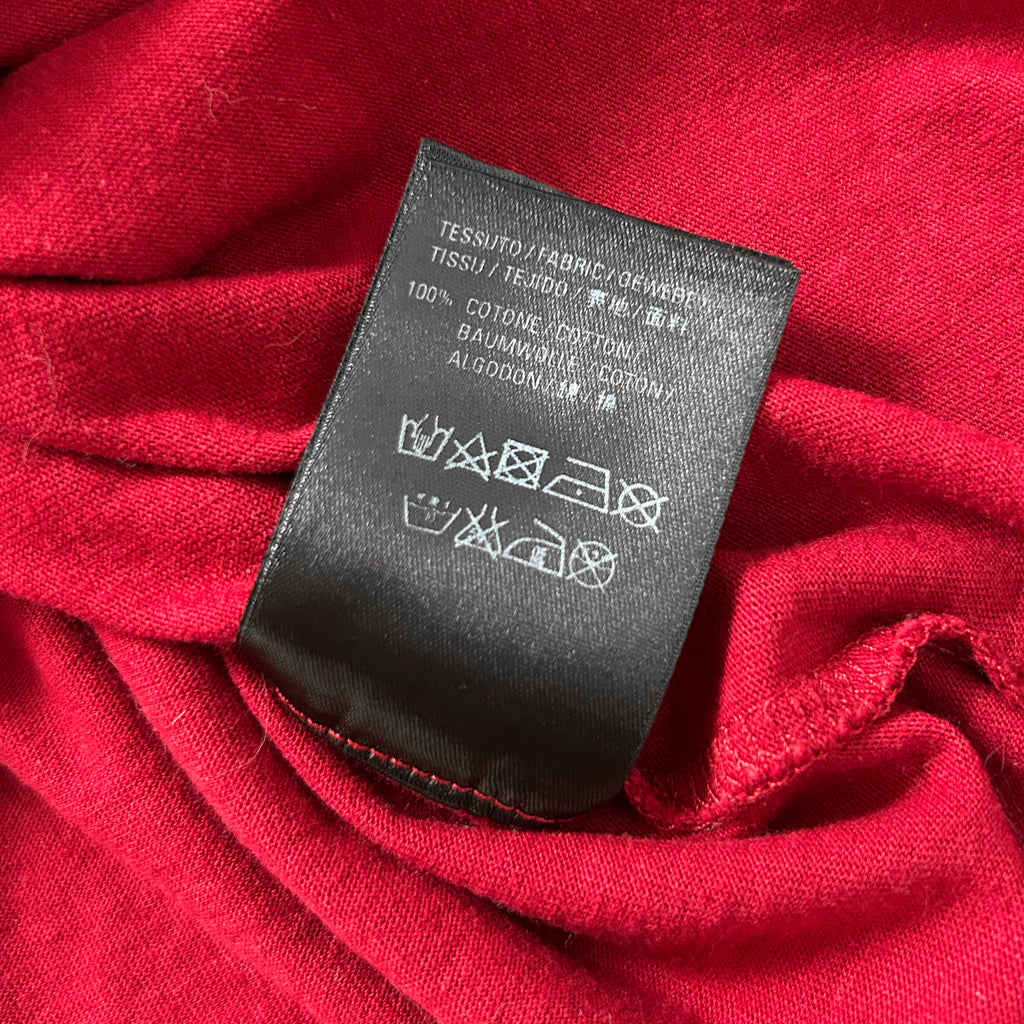 a close-up view of a red fabric with a black label attached to it, displaying text and symbols.