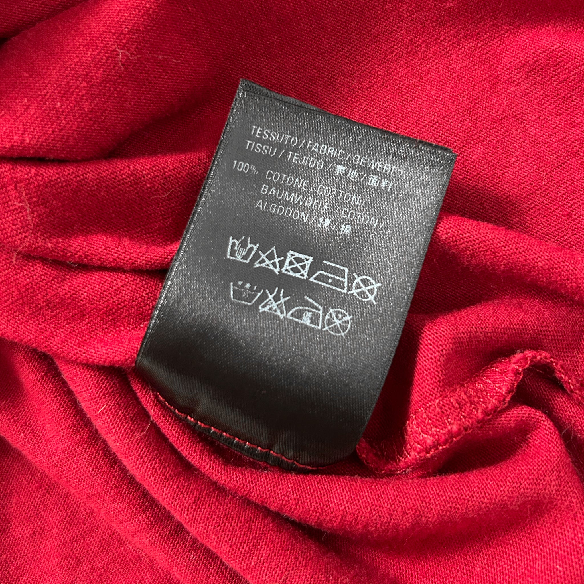 a close-up view of a red fabric with a black label attached to it, displaying text and symbols.
