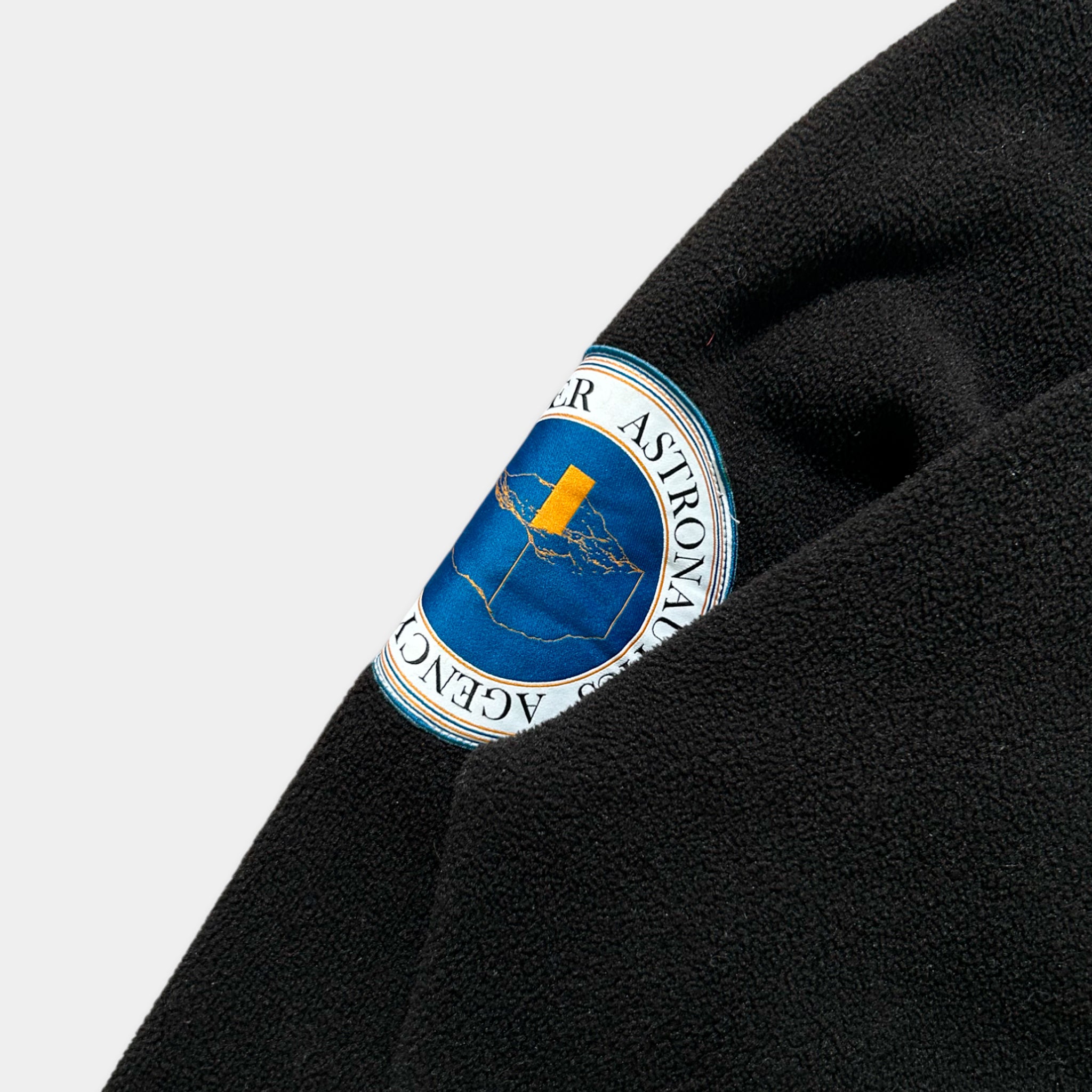 A close-up view of a black fabric with a circular blue and yellow logo on it.