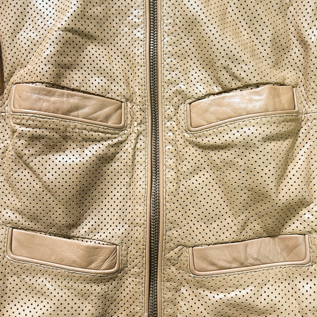 a close-up view of a beige leather jacket with two pockets and a zipper.