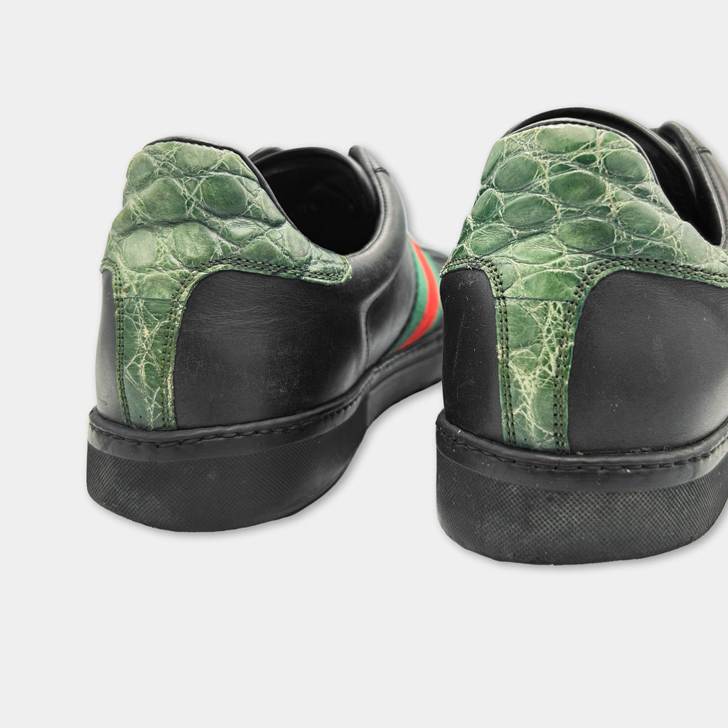 A pair of black Gucci sneakers with green and red accents.