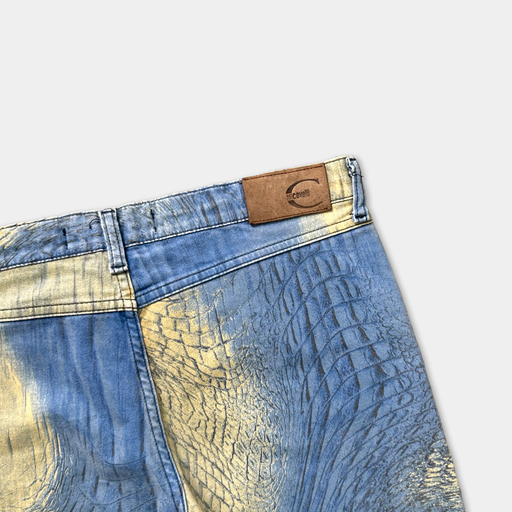 A pair of blue jeans with a unique pattern of blue and yellow colors, featuring a leather patch on the waistband.