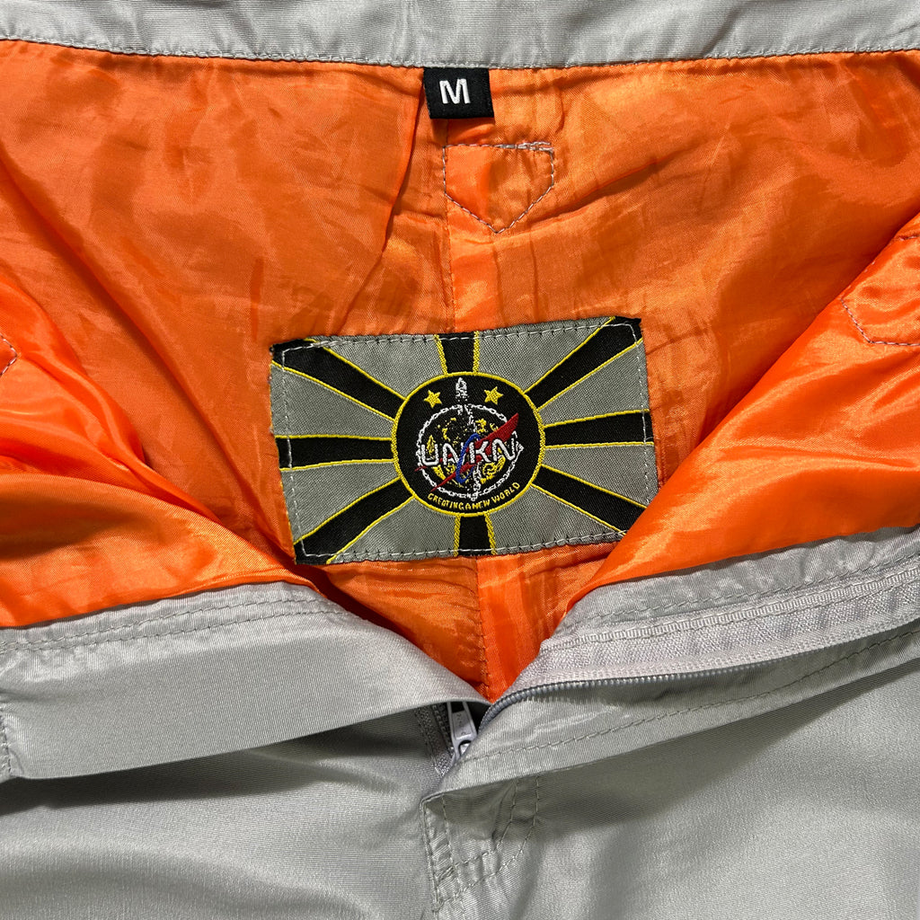 a close-up view of a grey and orange jacket with a label or patch on the back pocket.