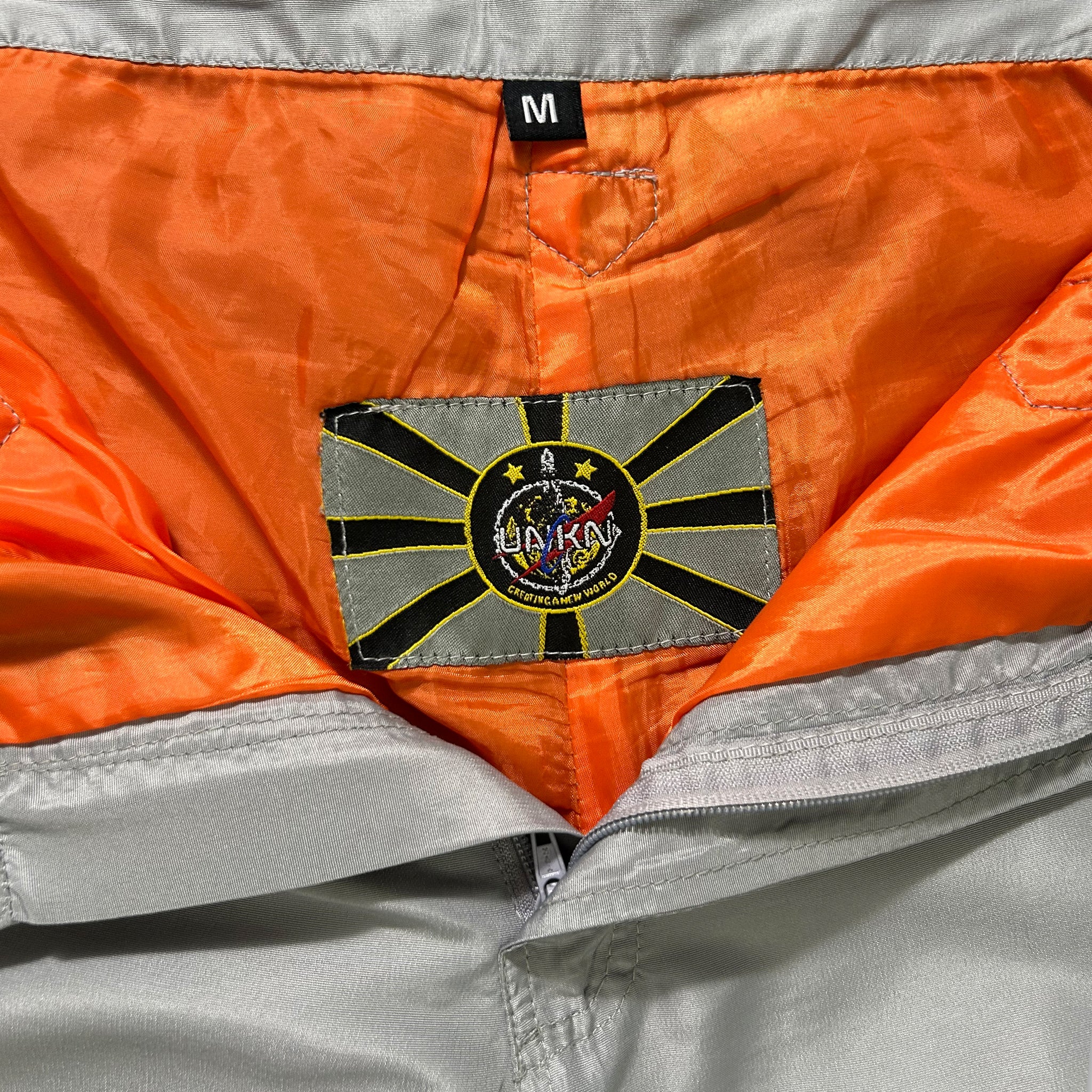 a close-up view of a grey and orange jacket with a label or patch on the back pocket.