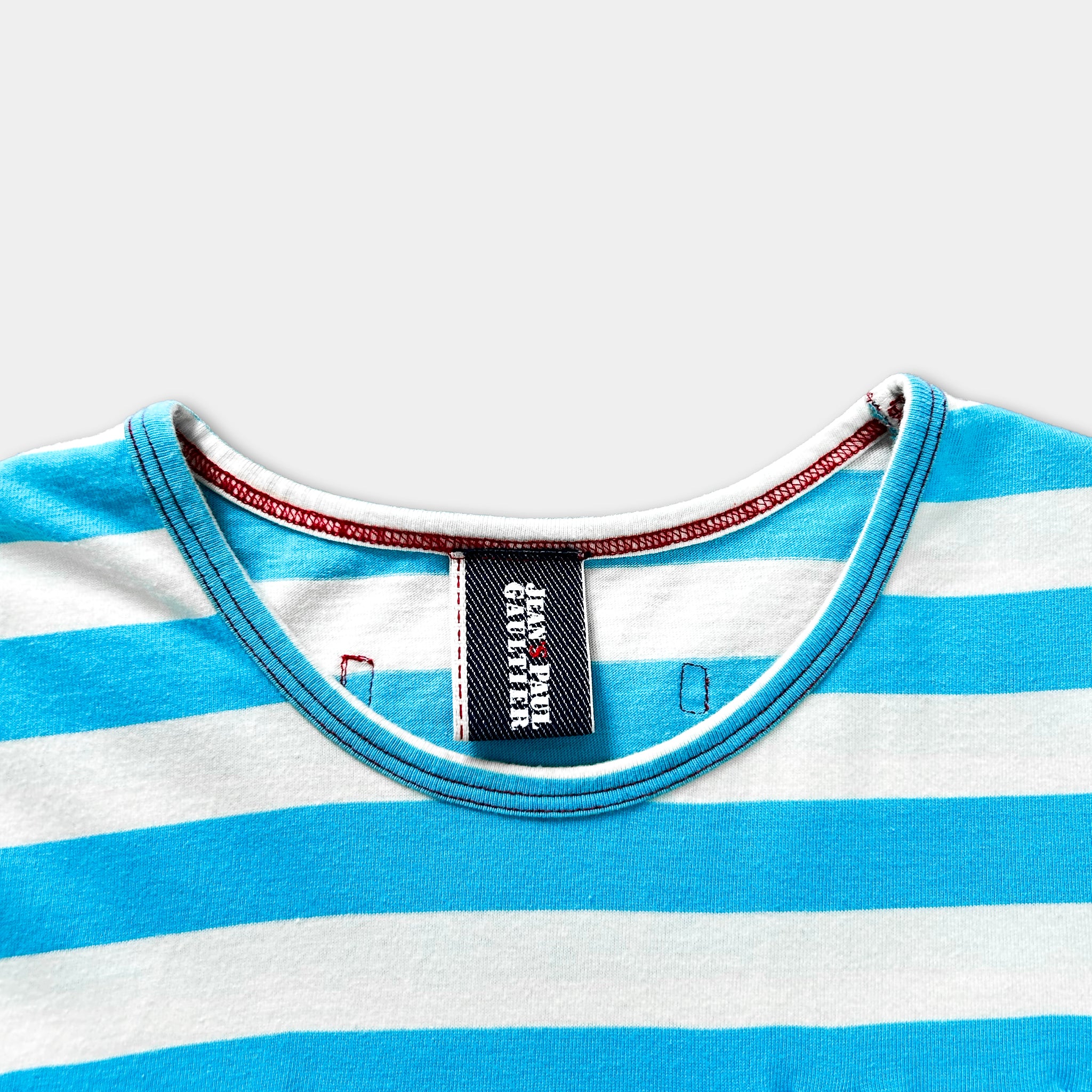 A close-up view of a blue and white striped shirt, with a red trim around the neckline.