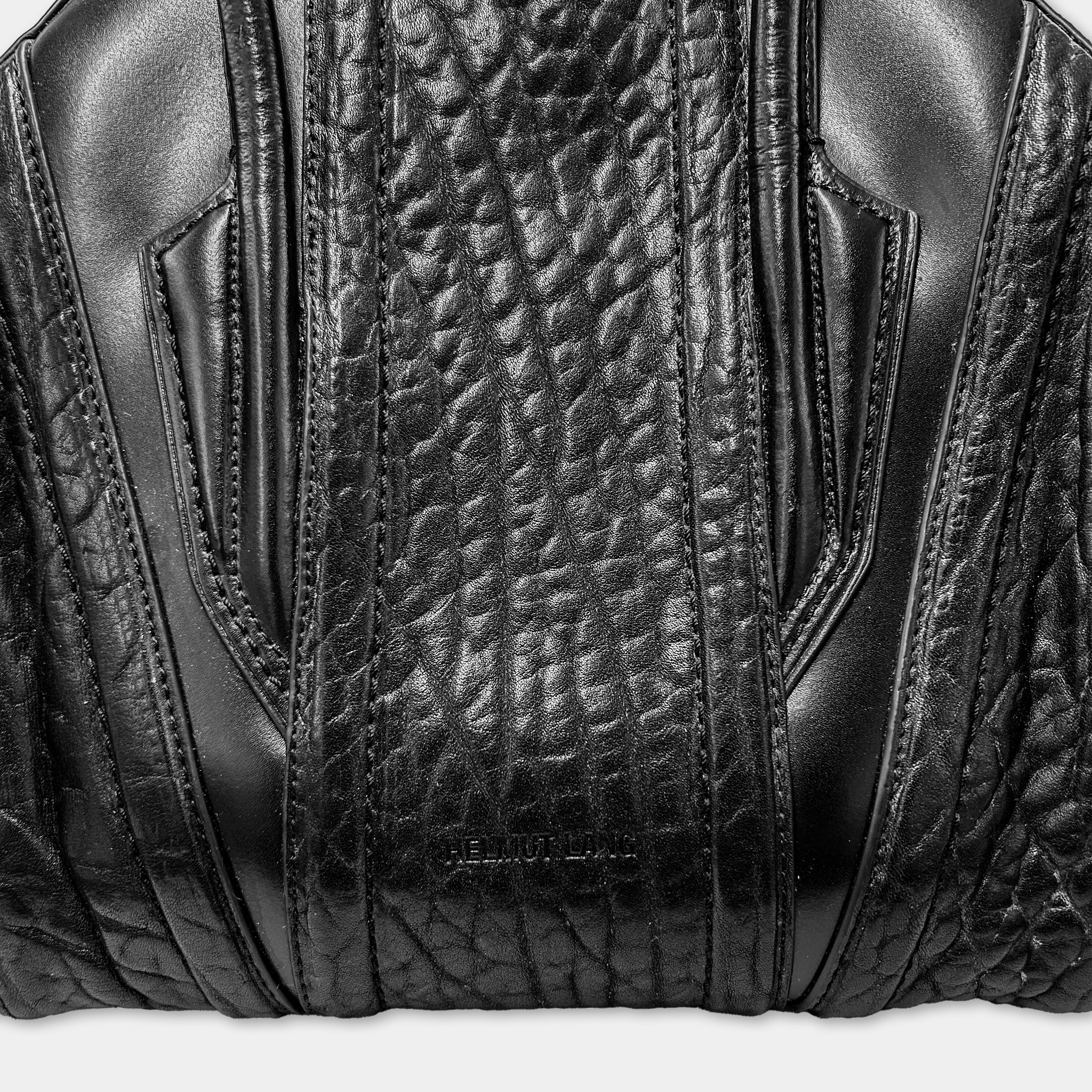 A close-up view of a black leather handbag, showcasing its detailed texture and design.
