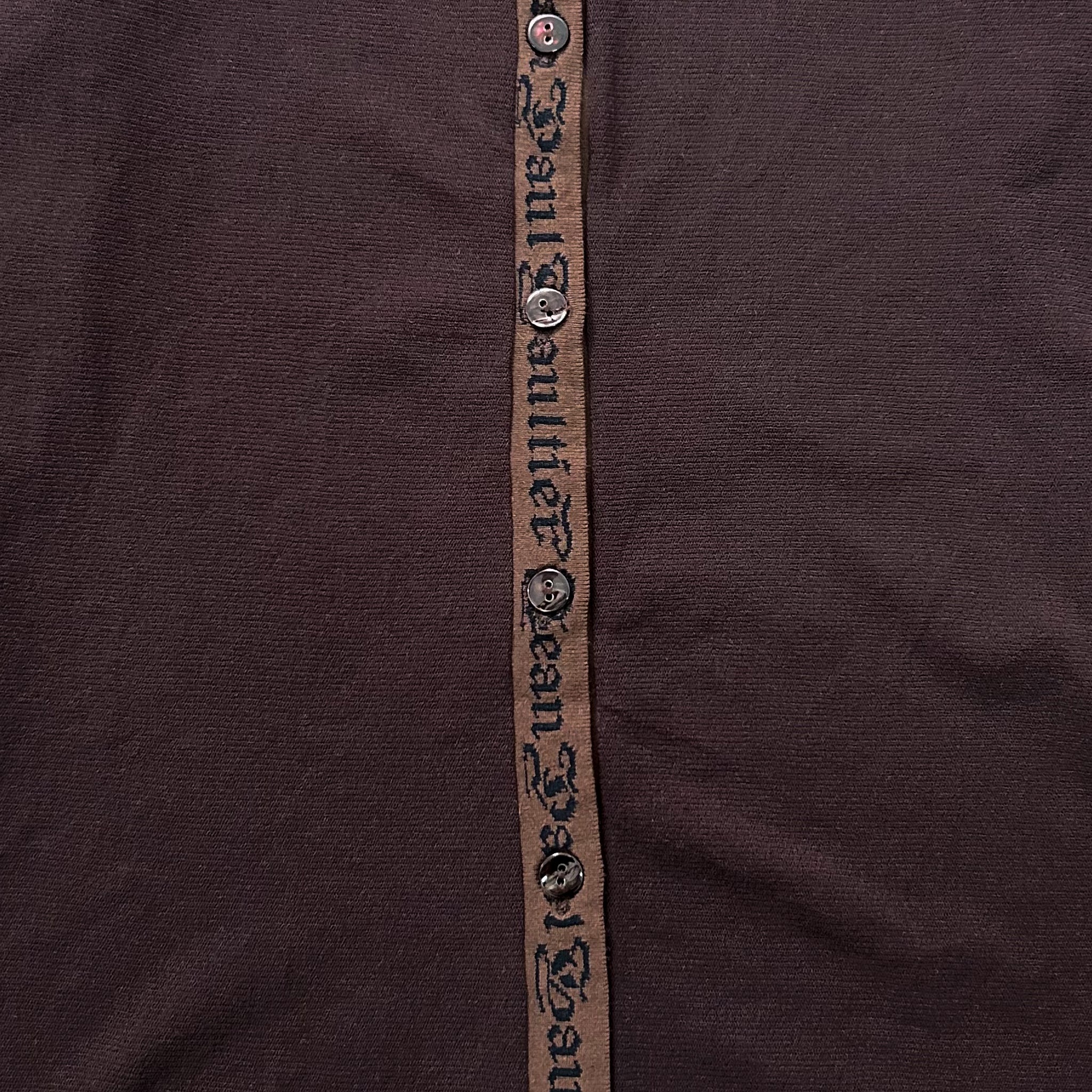 a close-up view of a dark brown fabric with a brown ribbon or strap running vertically down the center.