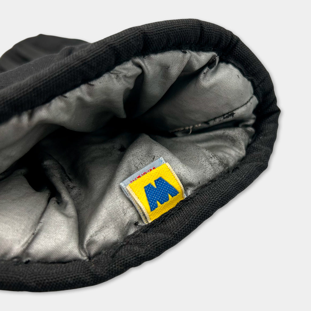 A close-up view of a black and gray fabric, possibly a piece of clothing or textile, with a yellow and blue label or patch on the inside.