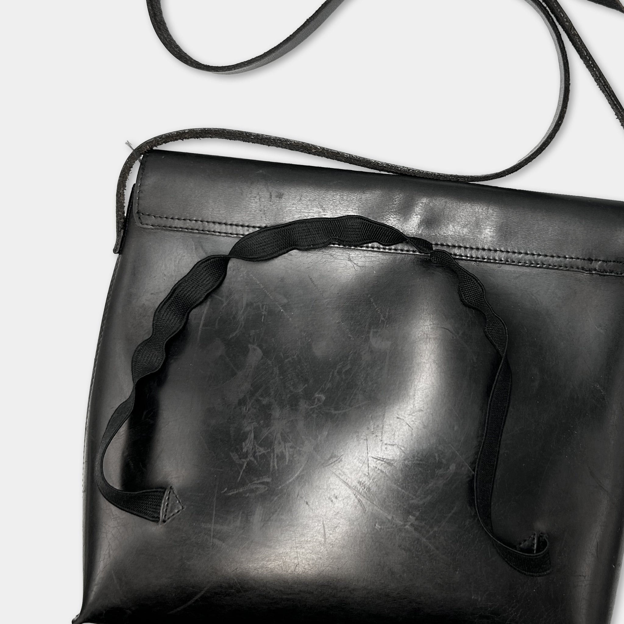A black leather handbag with a black strap and handle.