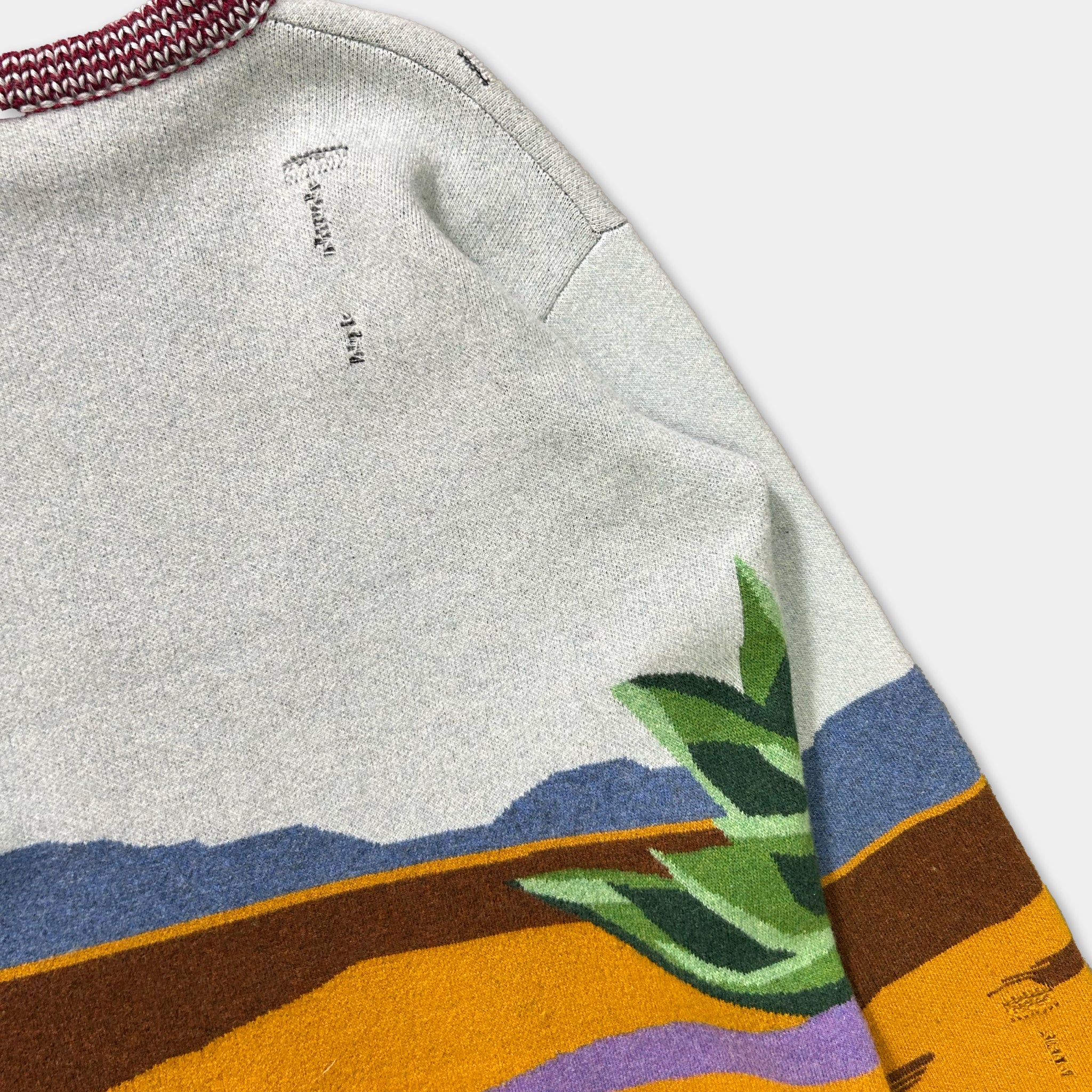a close-up view of a colorful sweater with a desert landscape design.