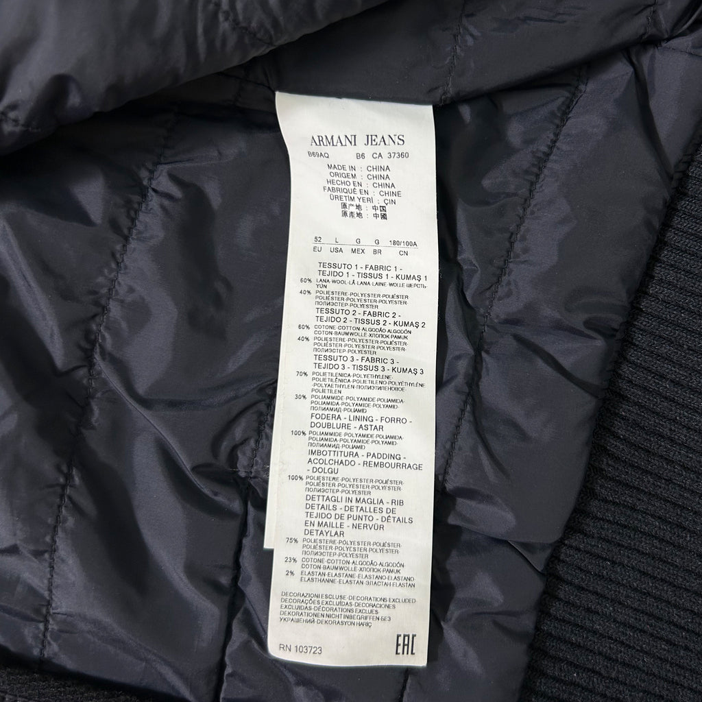 a close-up view of a black fabric, possibly a jacket or sweater, with a label attached to it. The label appears to be a product description or information sheet for the garment.