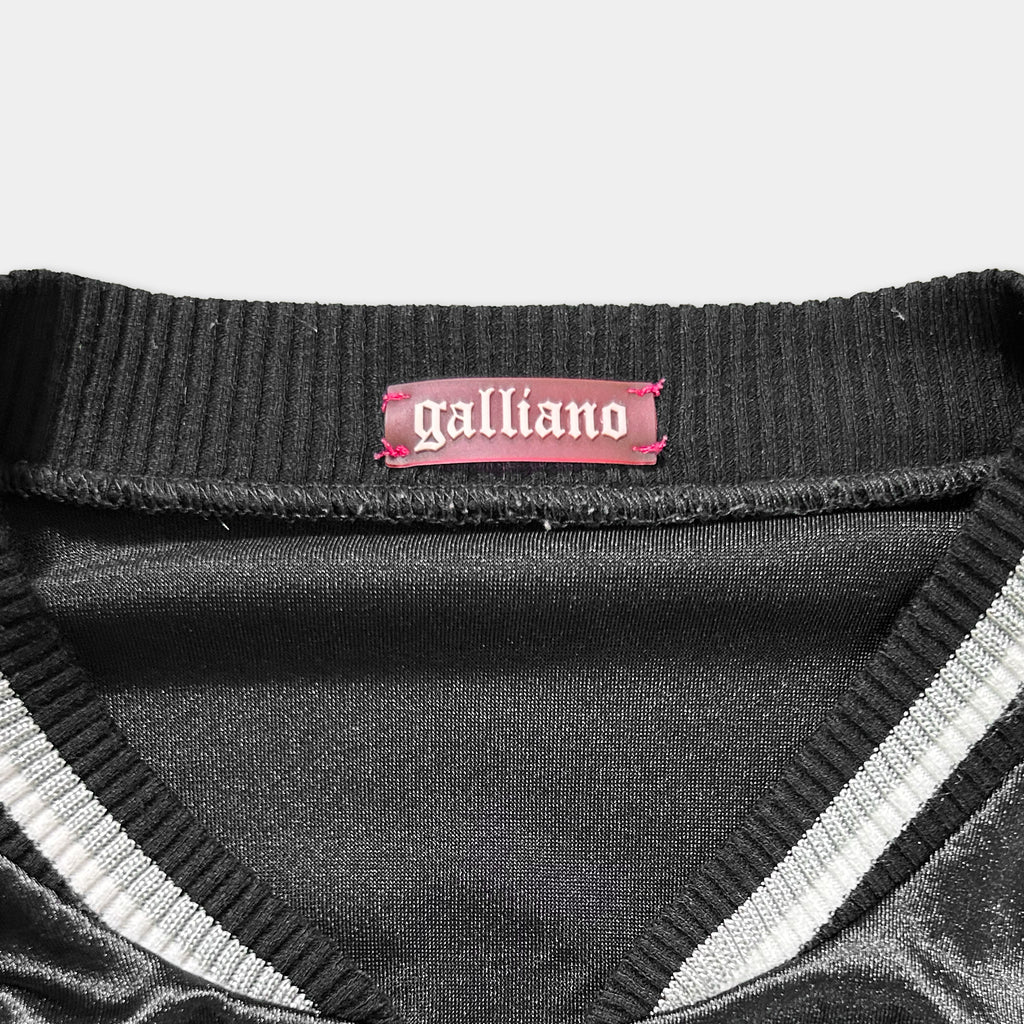 a close-up view of a black and white collar of a garment, with a pink label attached to it that reads "galliano".