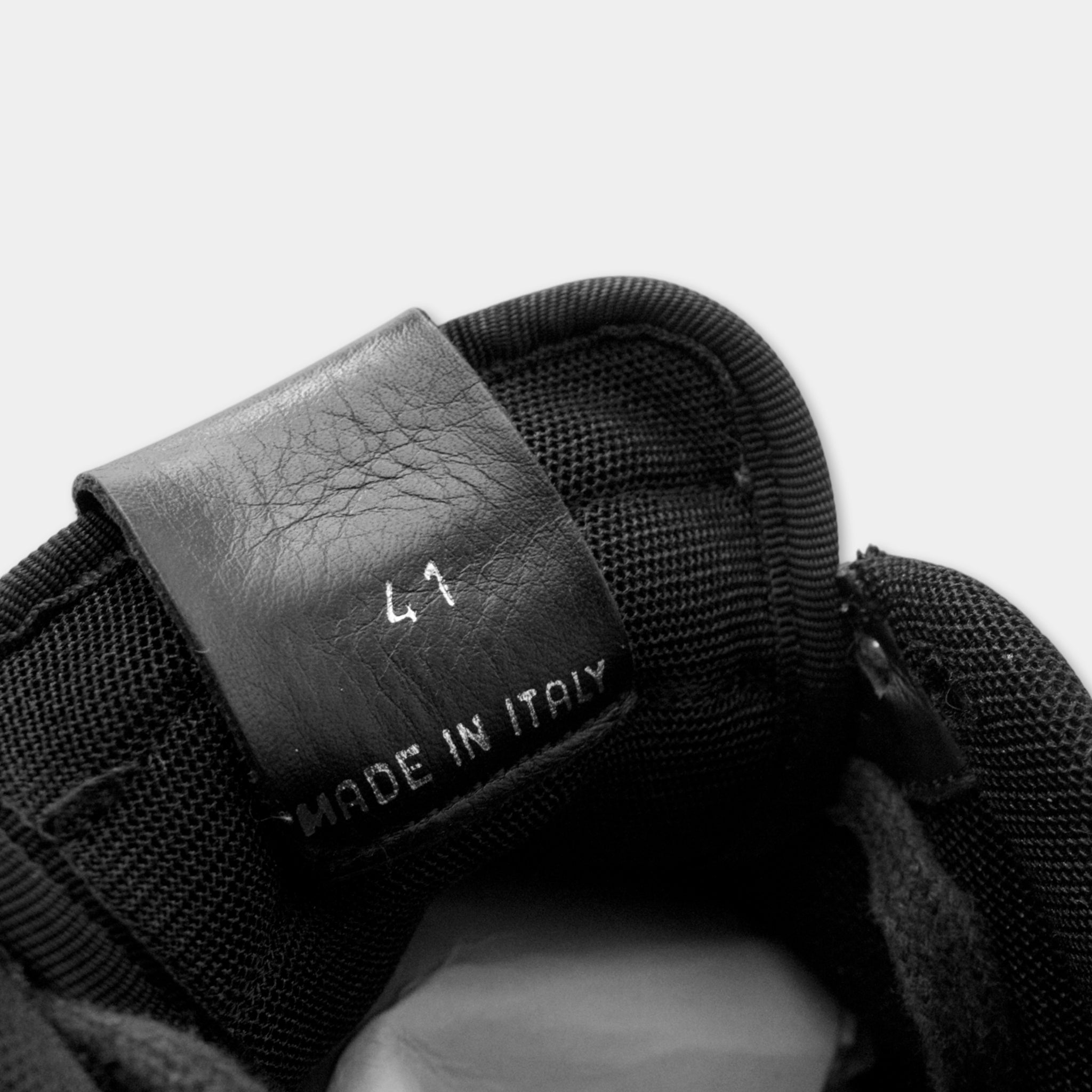 A close-up view of a black shoe label with the text "MADE IN ITALY" printed on it.