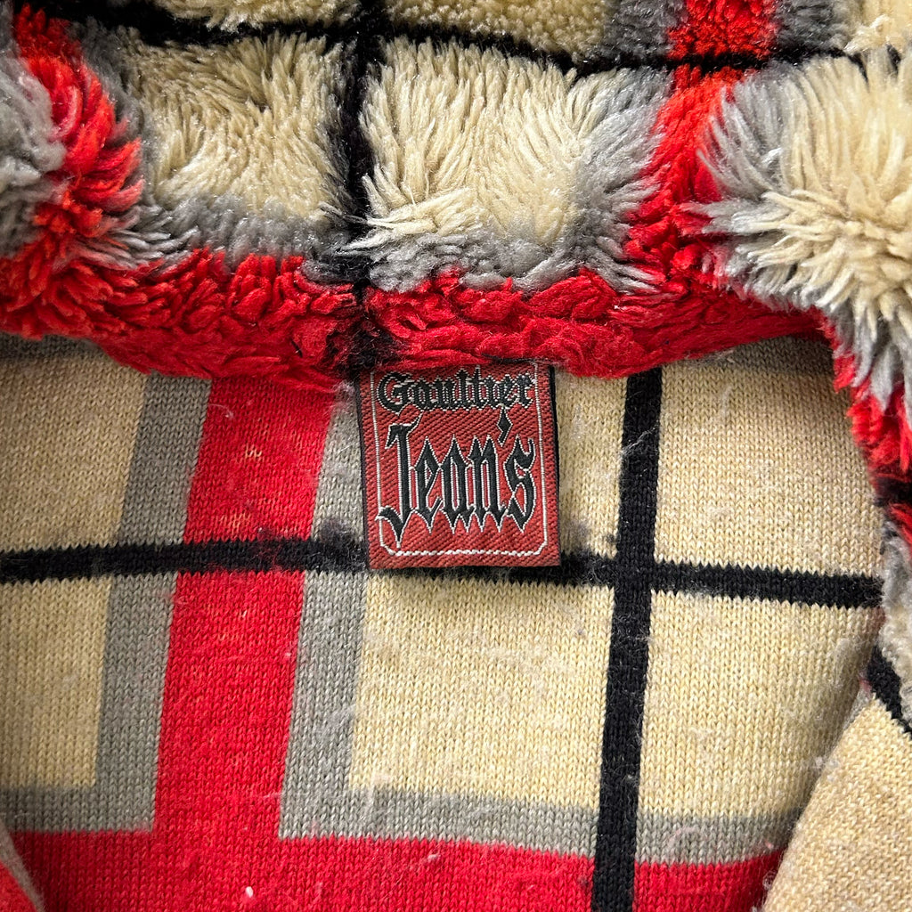 a close-up view of a red and gray plaid fabric with a red and black label that reads "Gaucher Jeans" attached to it.