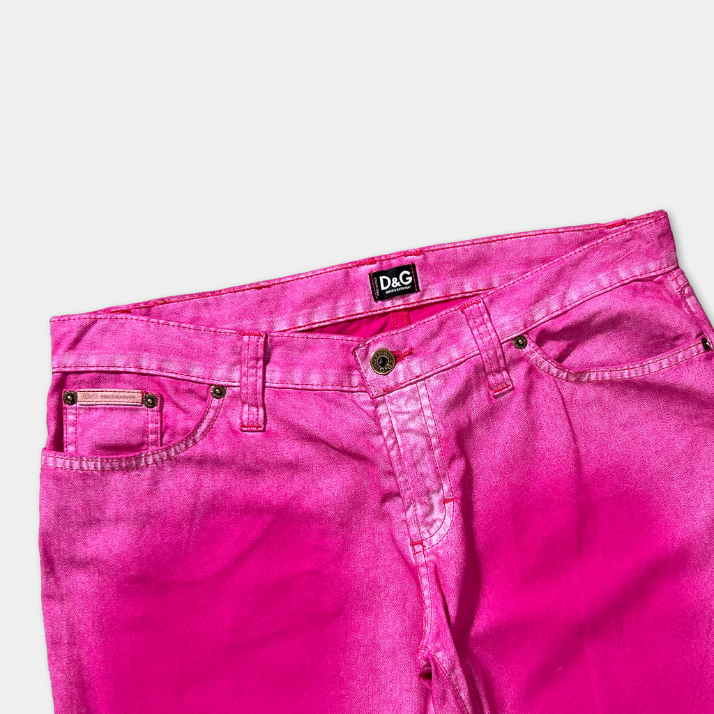 A pair of bright pink, high-waisted jeans with a black label on the waistband.
