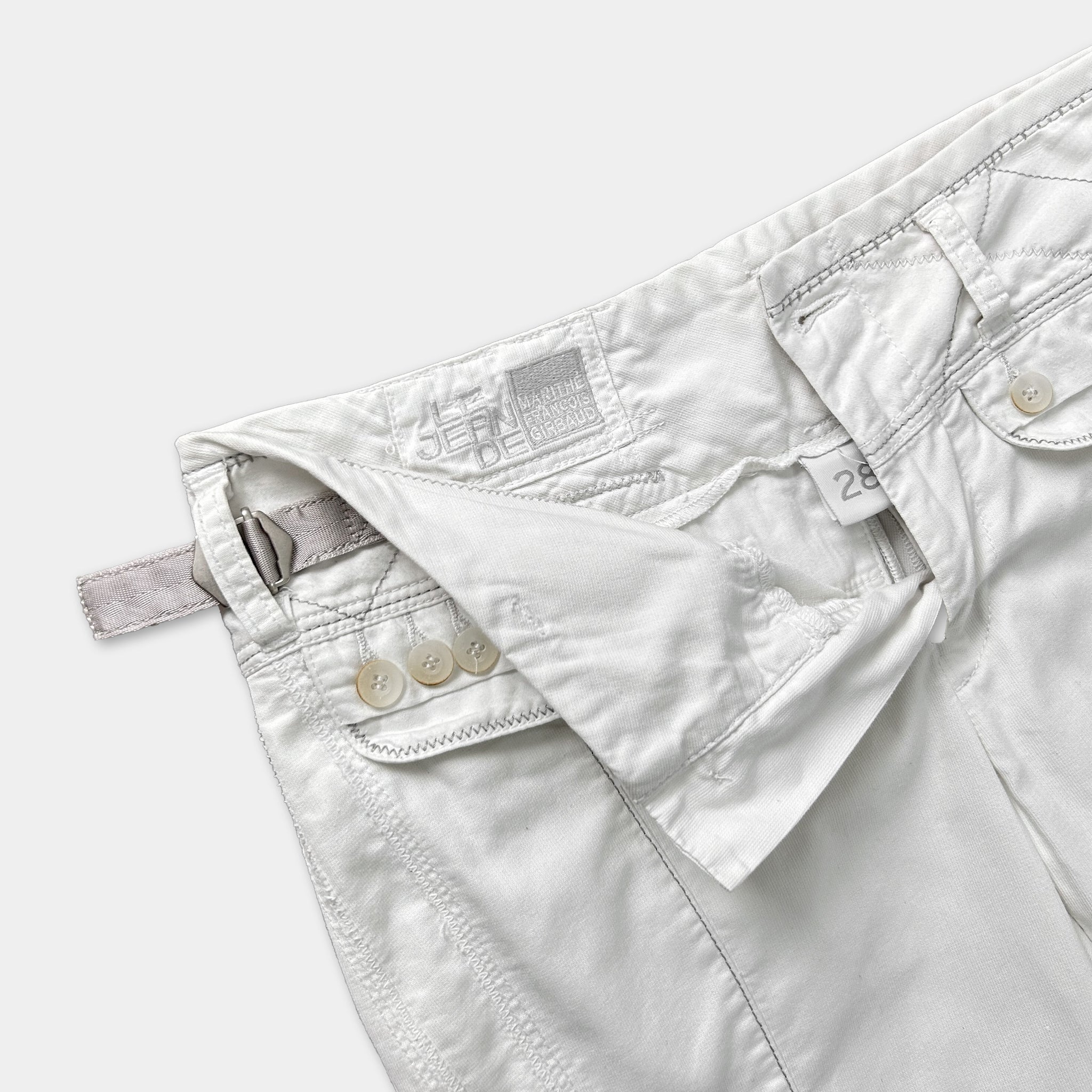 A close-up view of a pair of white pants with a label on the waistband.