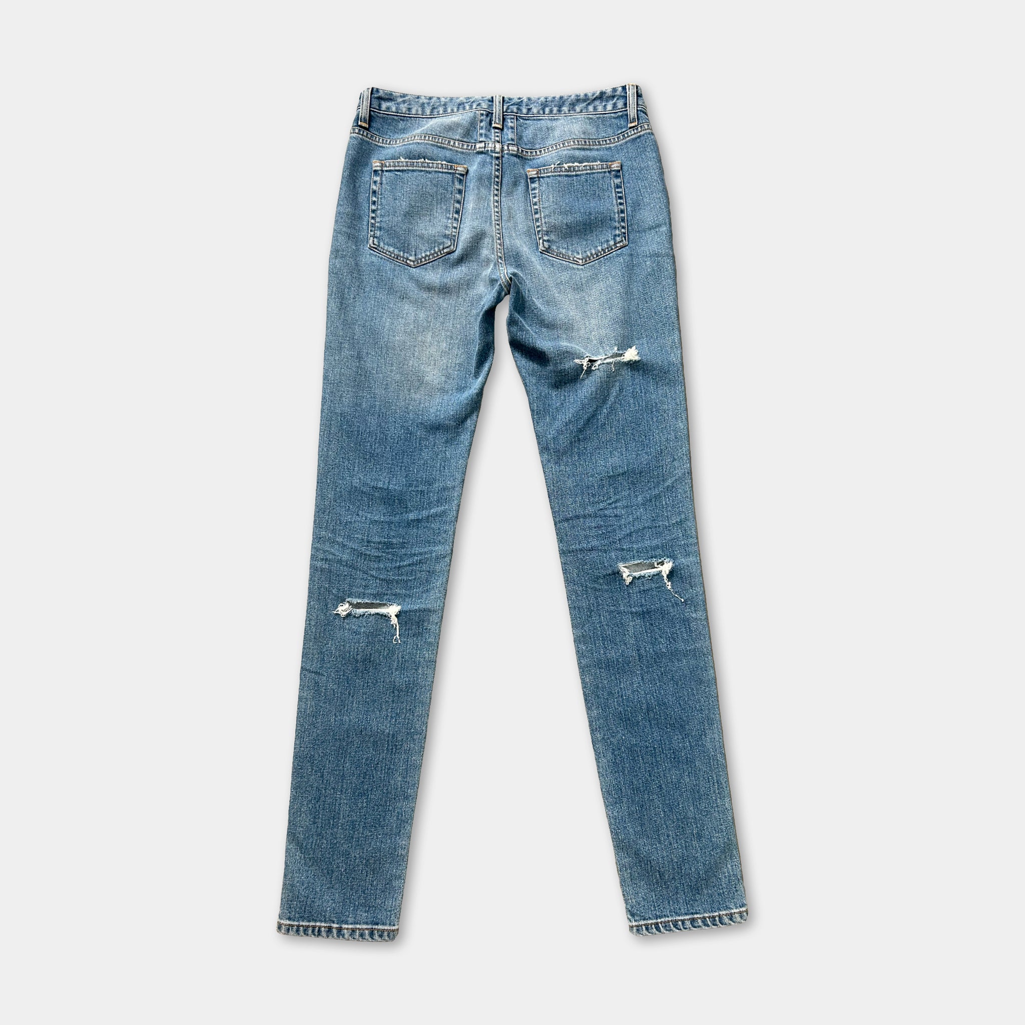 A pair of blue jeans with visible holes and frayed edges, suggesting they are well-worn.