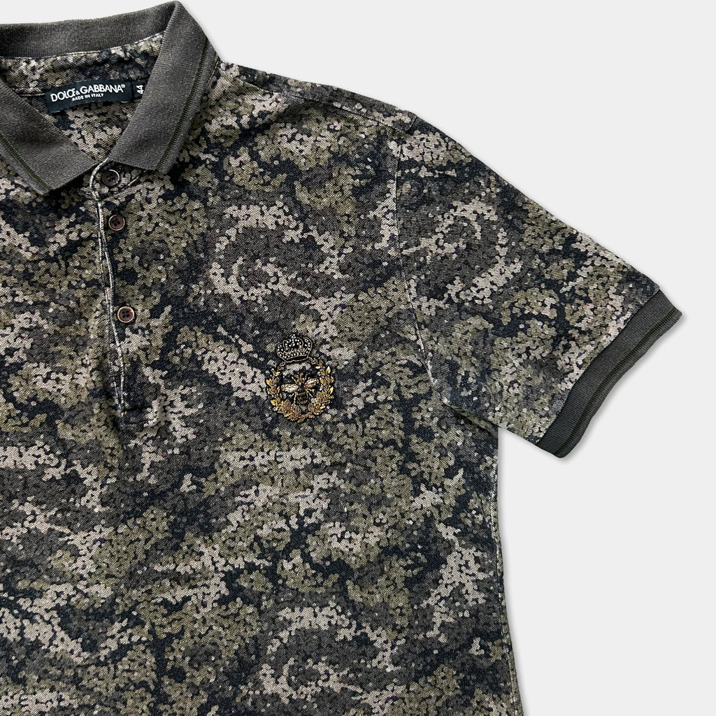 A camouflage-patterned polo shirt with a gold emblem on the left side.