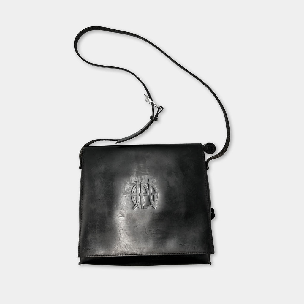 A black leather satchel with a monogrammed logo on the front.