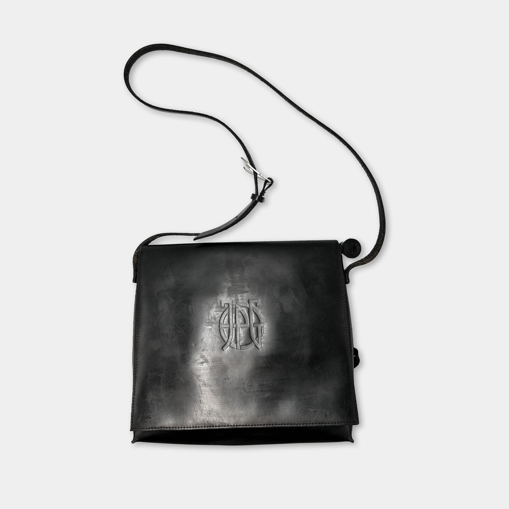 A black leather satchel with a monogrammed logo on the front.