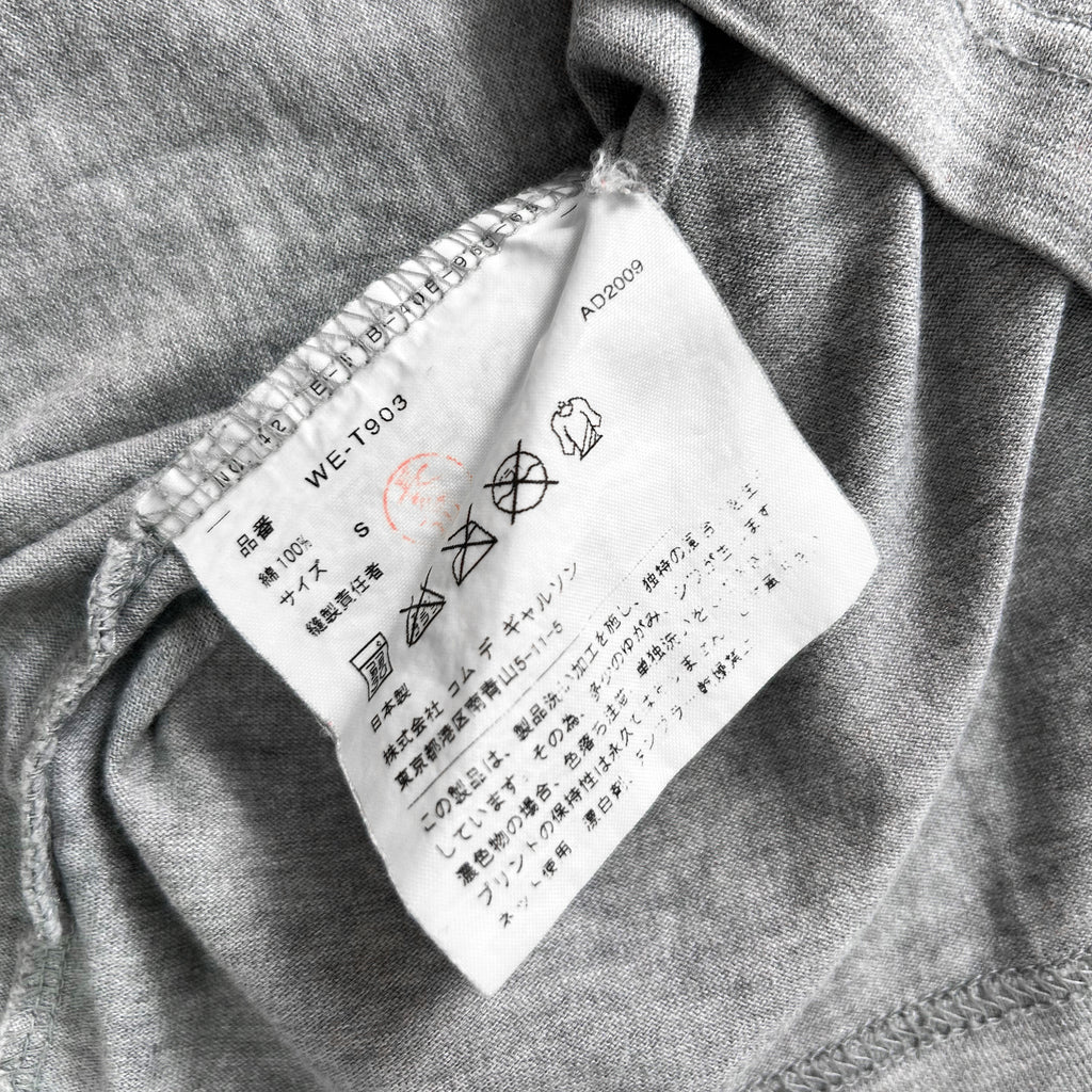 a close-up view of a white label with black text and symbols on a gray fabric background.